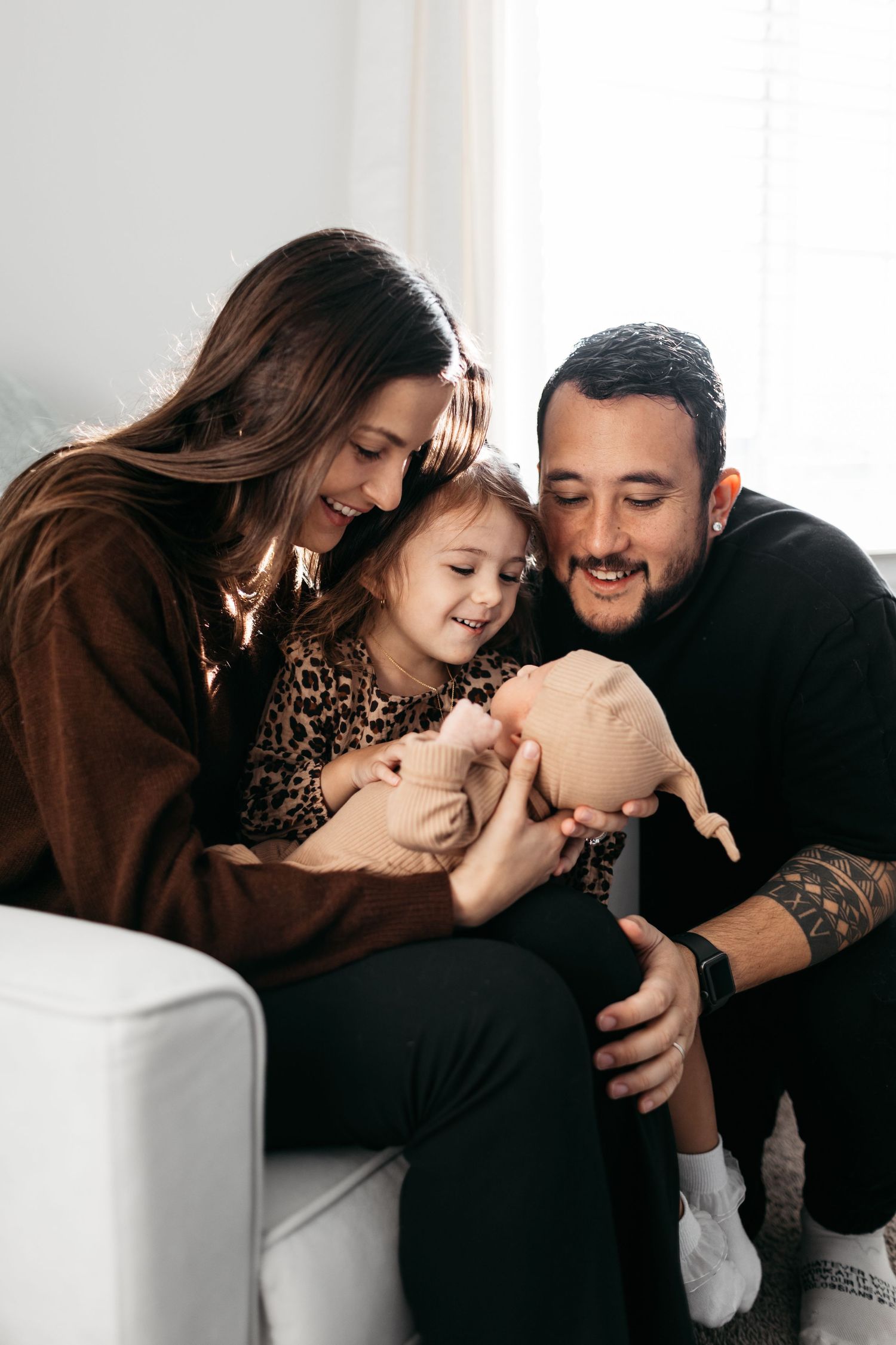 Intimate family moments captured in bright indoor setting with soft white background.