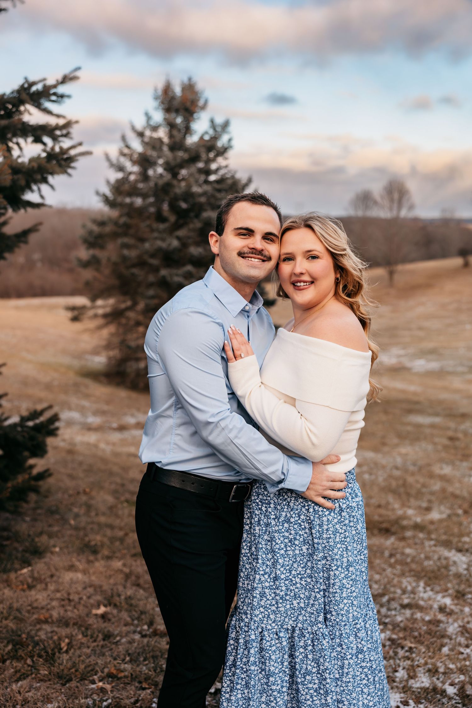 Romantic couple's portrait session in a winter field at sunset.