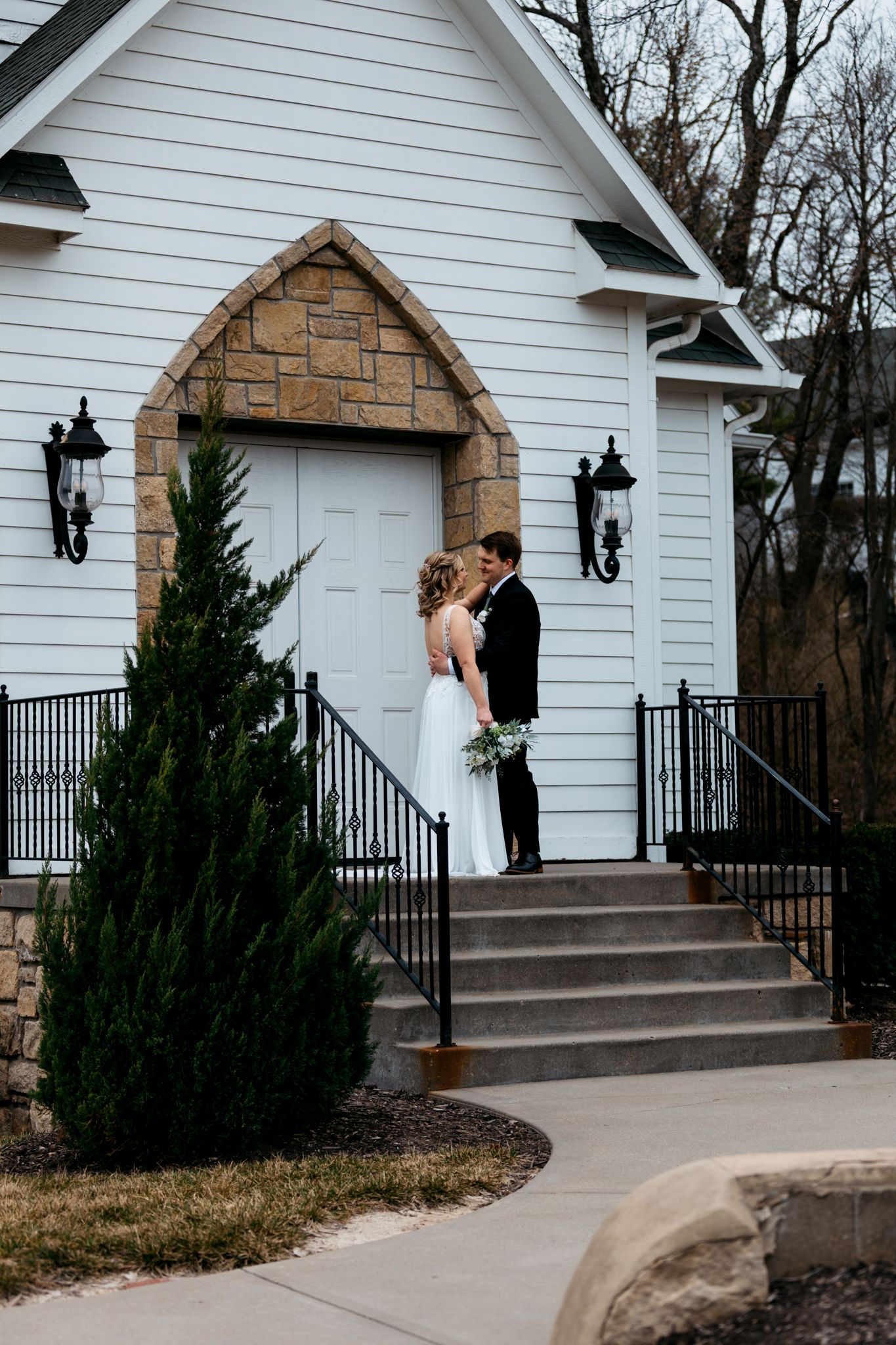 Classic white chapel entrance frames newlyweds during romantic wedding day portraits.