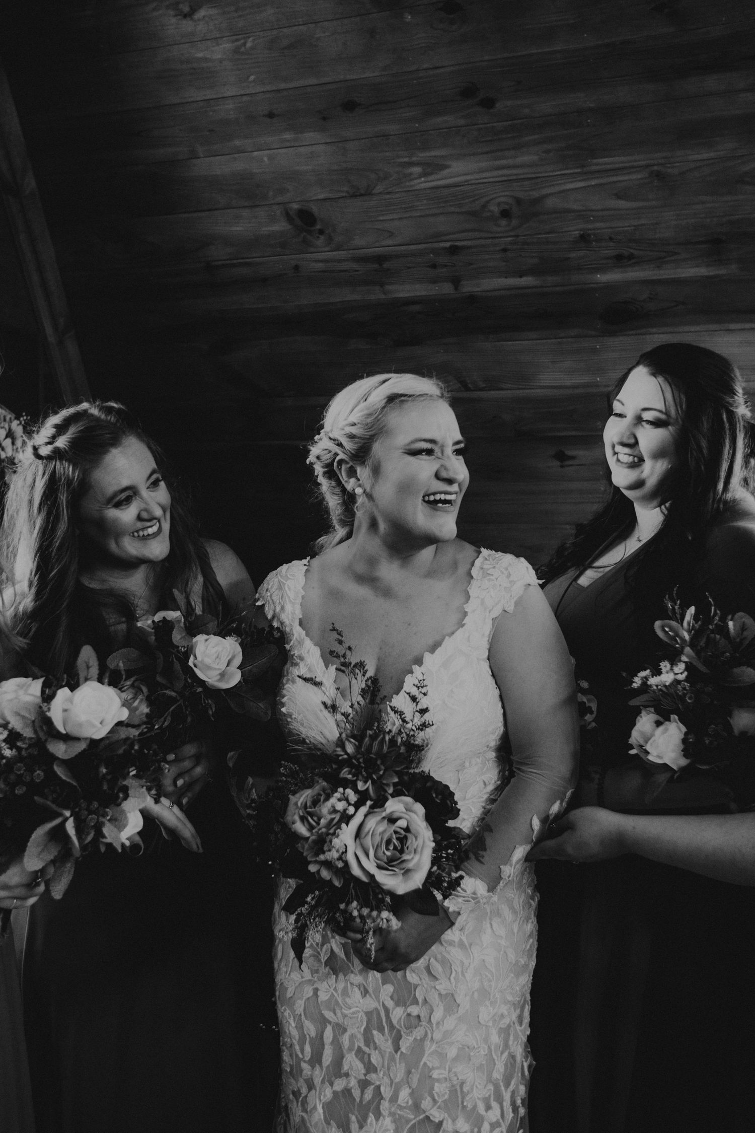 Black and white candid photo of wedding party laughing together.