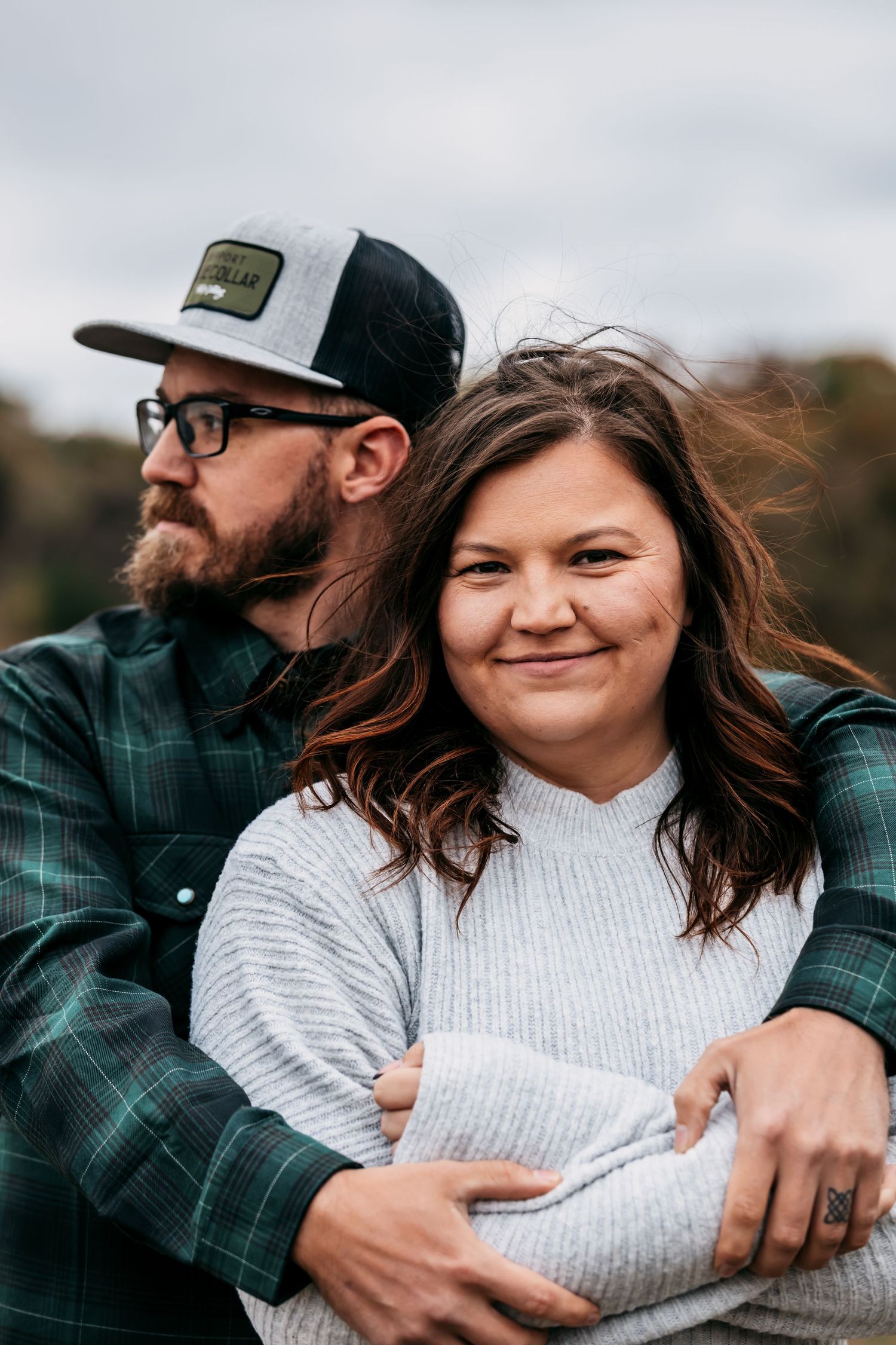A couple shares an intimate embrace while wearing cozy sweaters during a fall photoshoot.