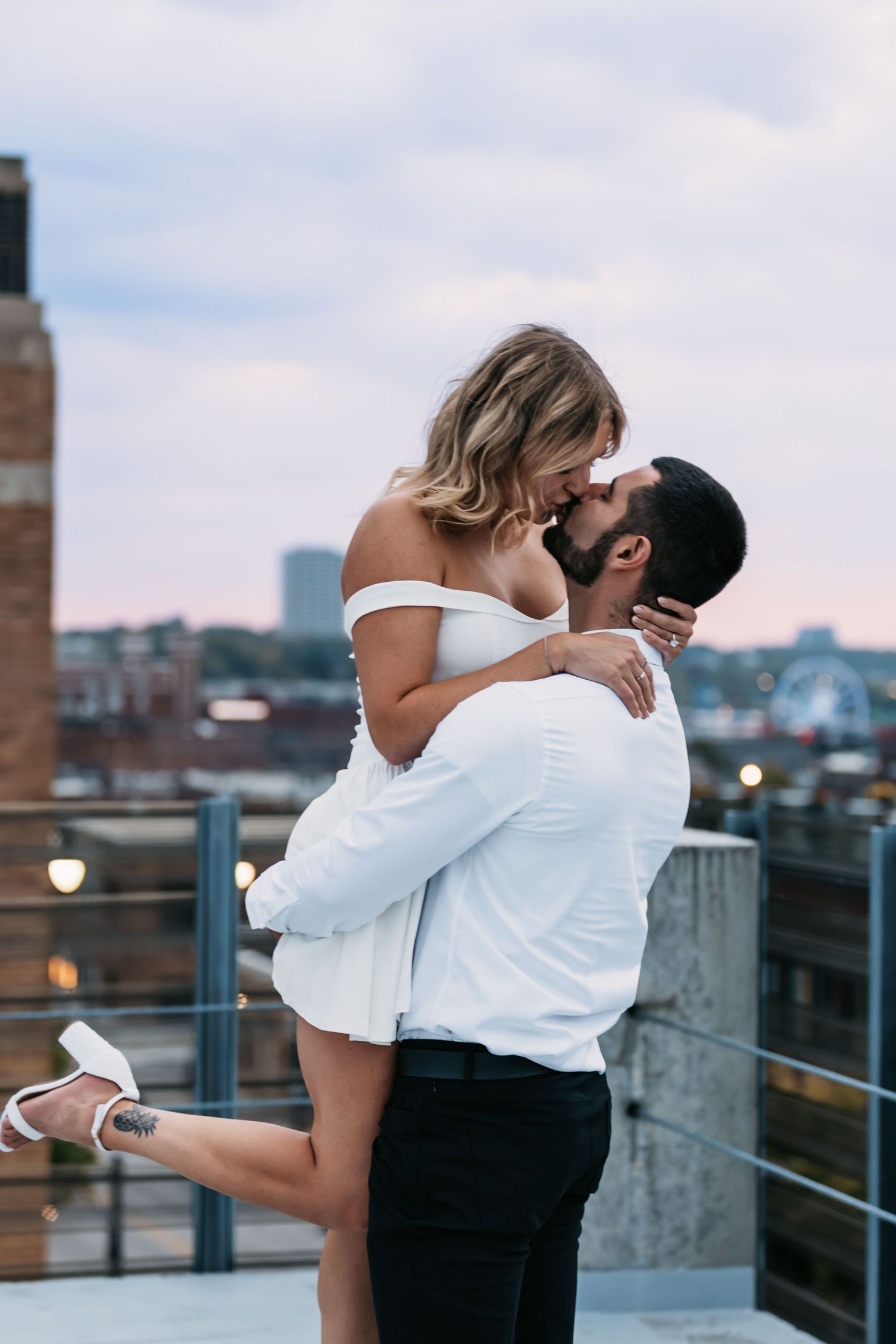 Romantic couple embracing on a rooftop with city buildings in the background.