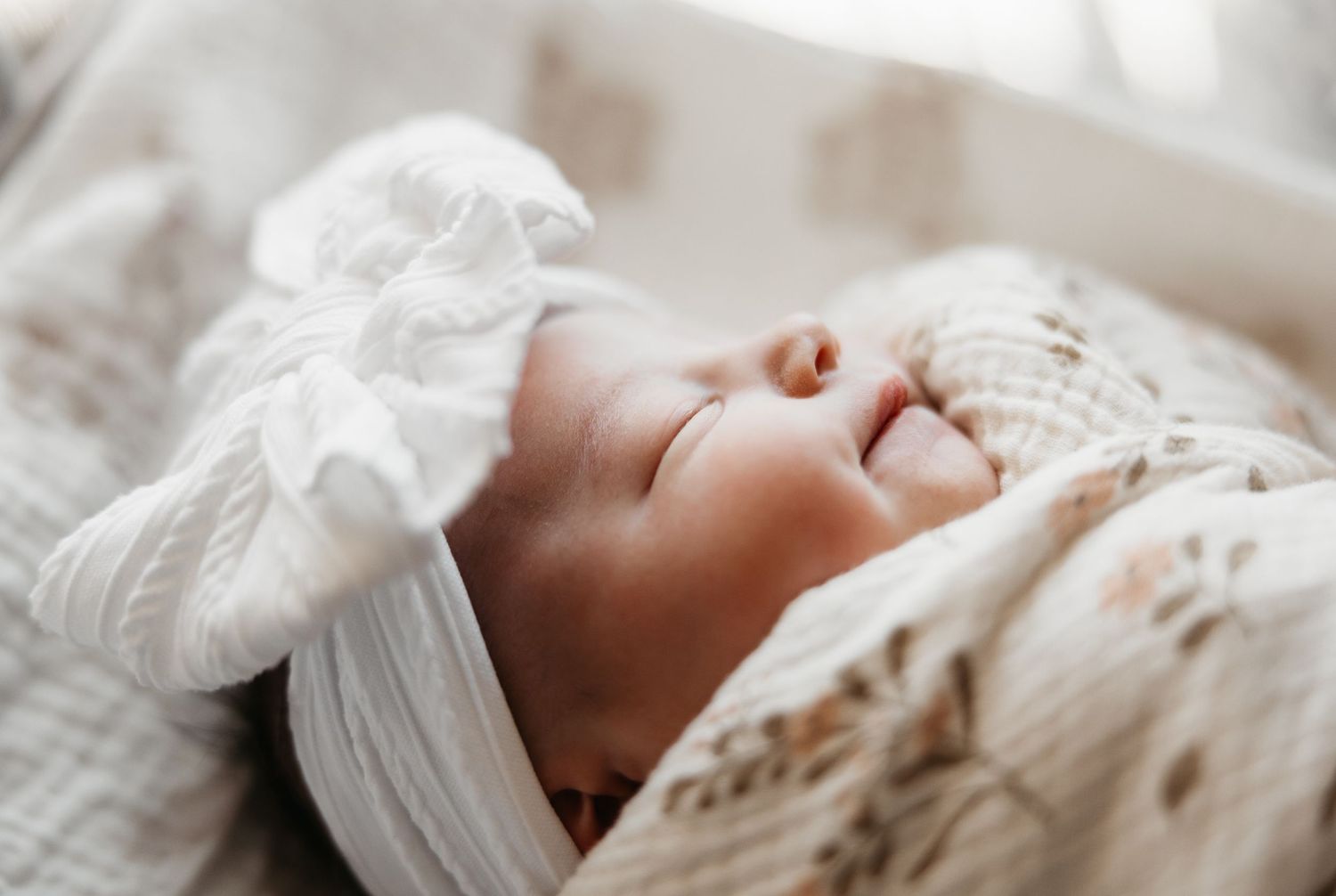 A sequence of photos showing a newborn baby sleeping peacefully in white swaddling blankets.