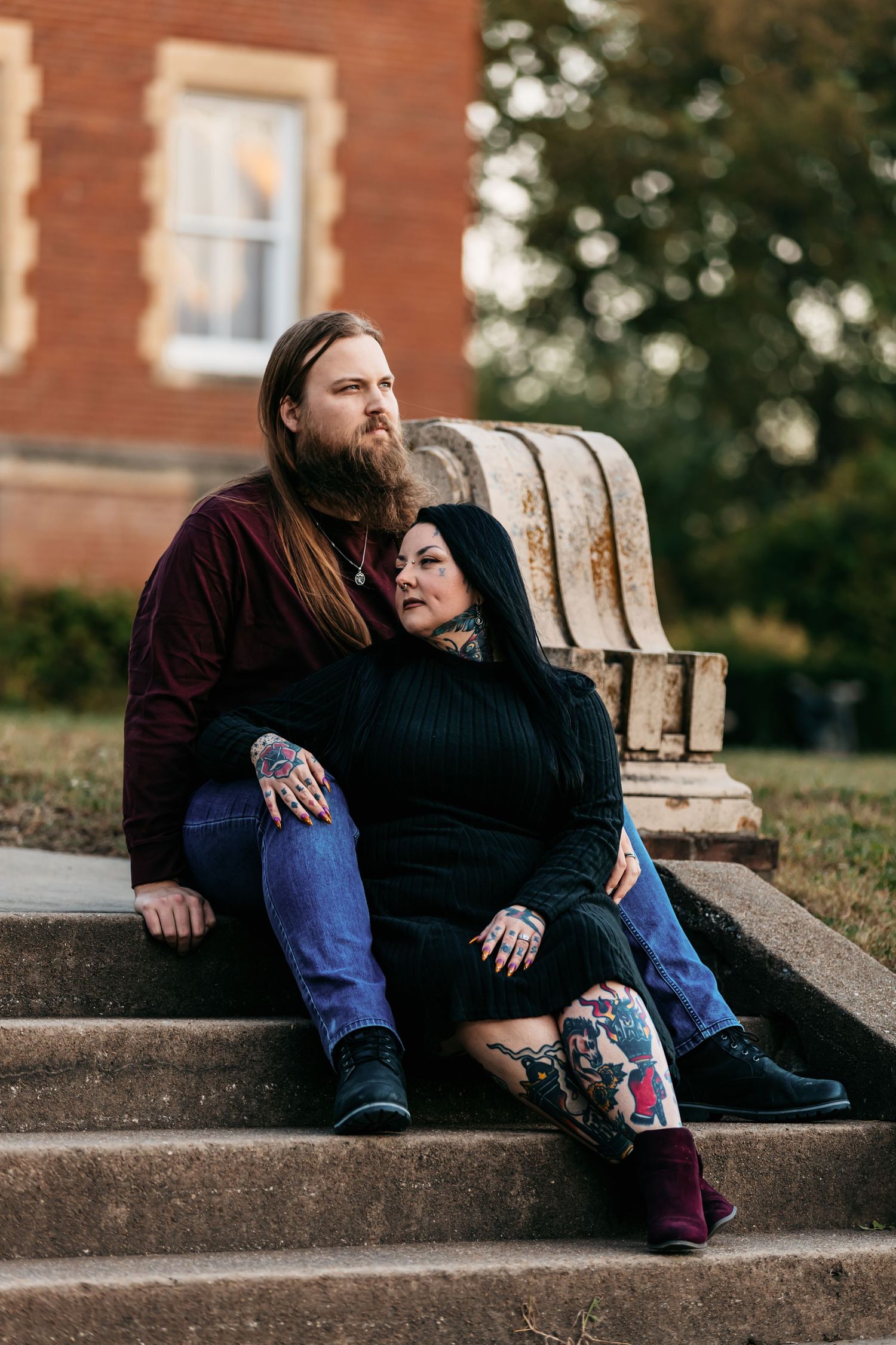 A couple snuggles together on concrete steps during an autumn sunset photoshoot.