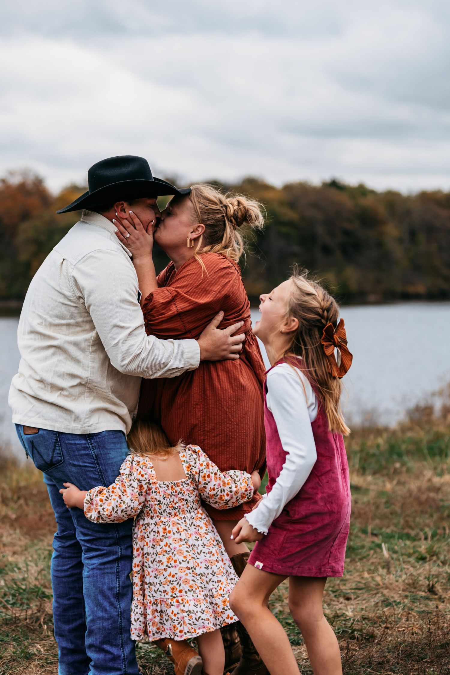 Family sharing loving moments together in an autumn field by the water.