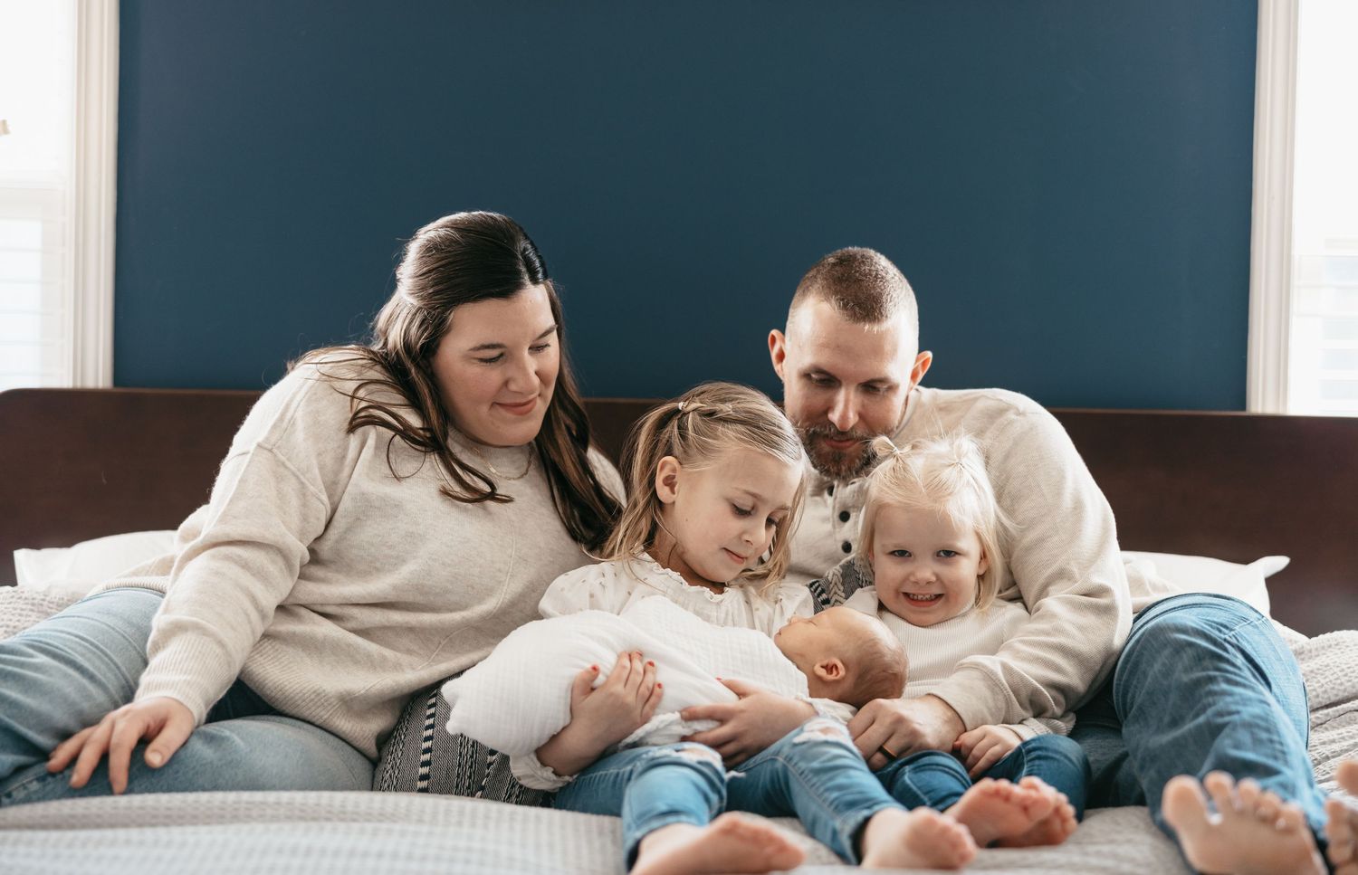 Family in matching cream sweaters sharing tender moments on blue couch.