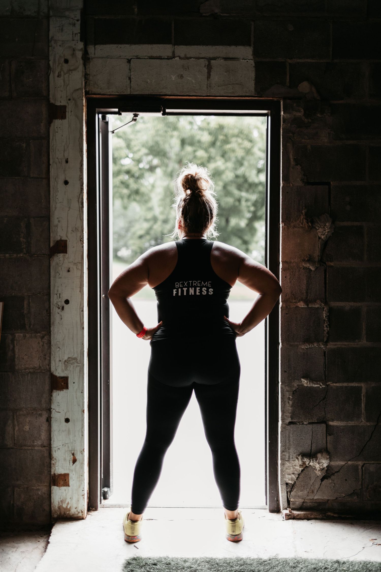 Silhouette of person in fitness attire standing in doorway with dramatic backlighting.