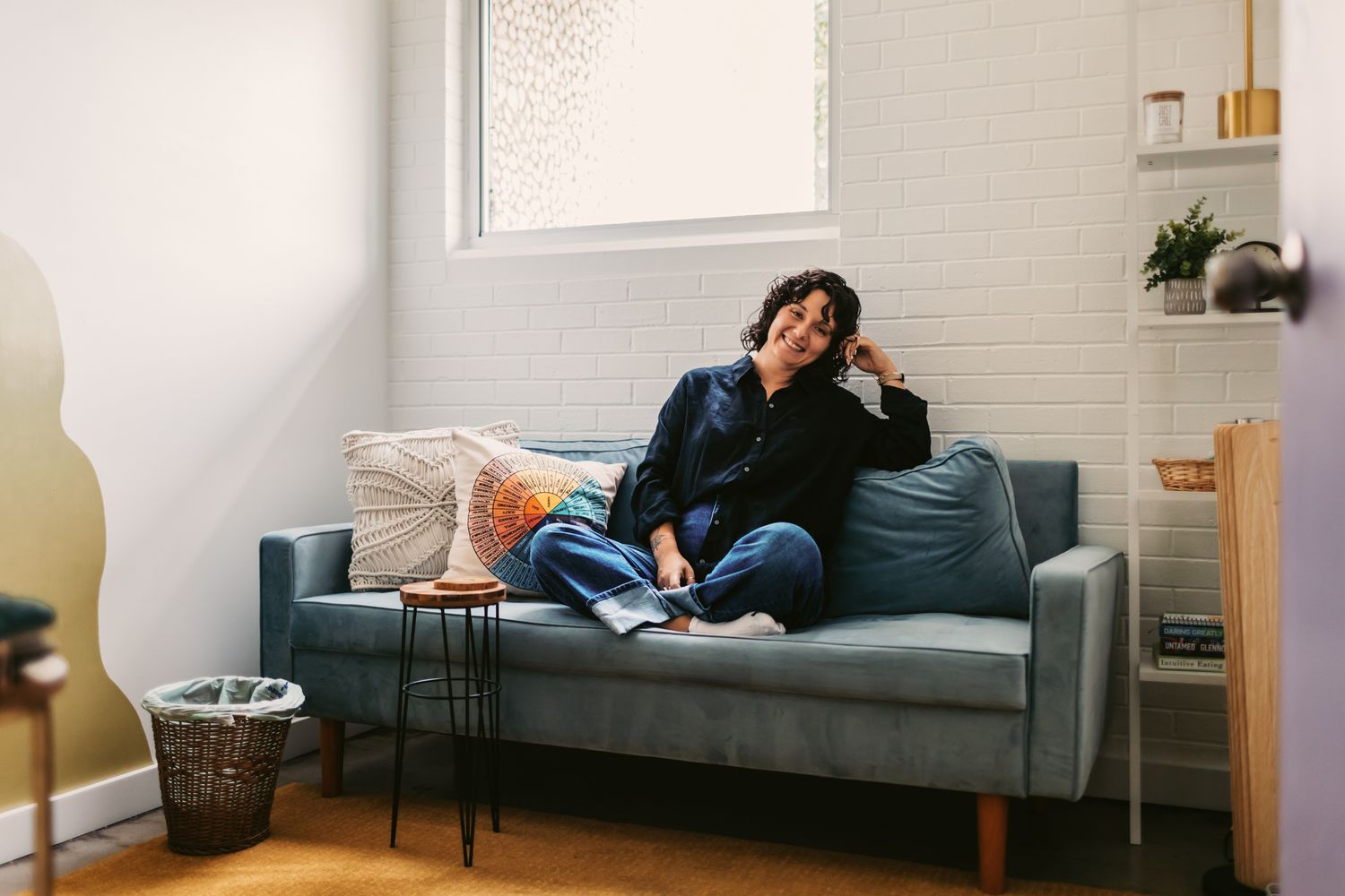 Minimalist panoramic view of person relaxing on gray couch in bright room.