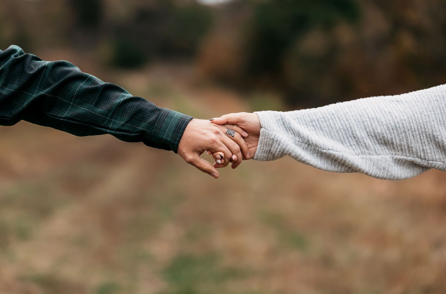 Close-up shot of two hands reaching out to connect against a blurred background.