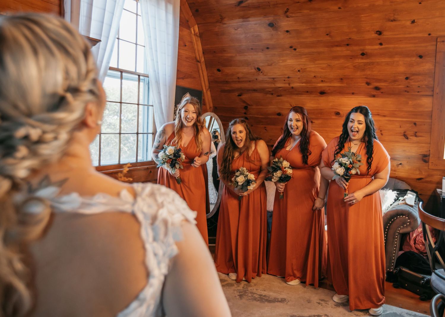 Bridal party shares emotional moments in a rustic wooden cabin interior.