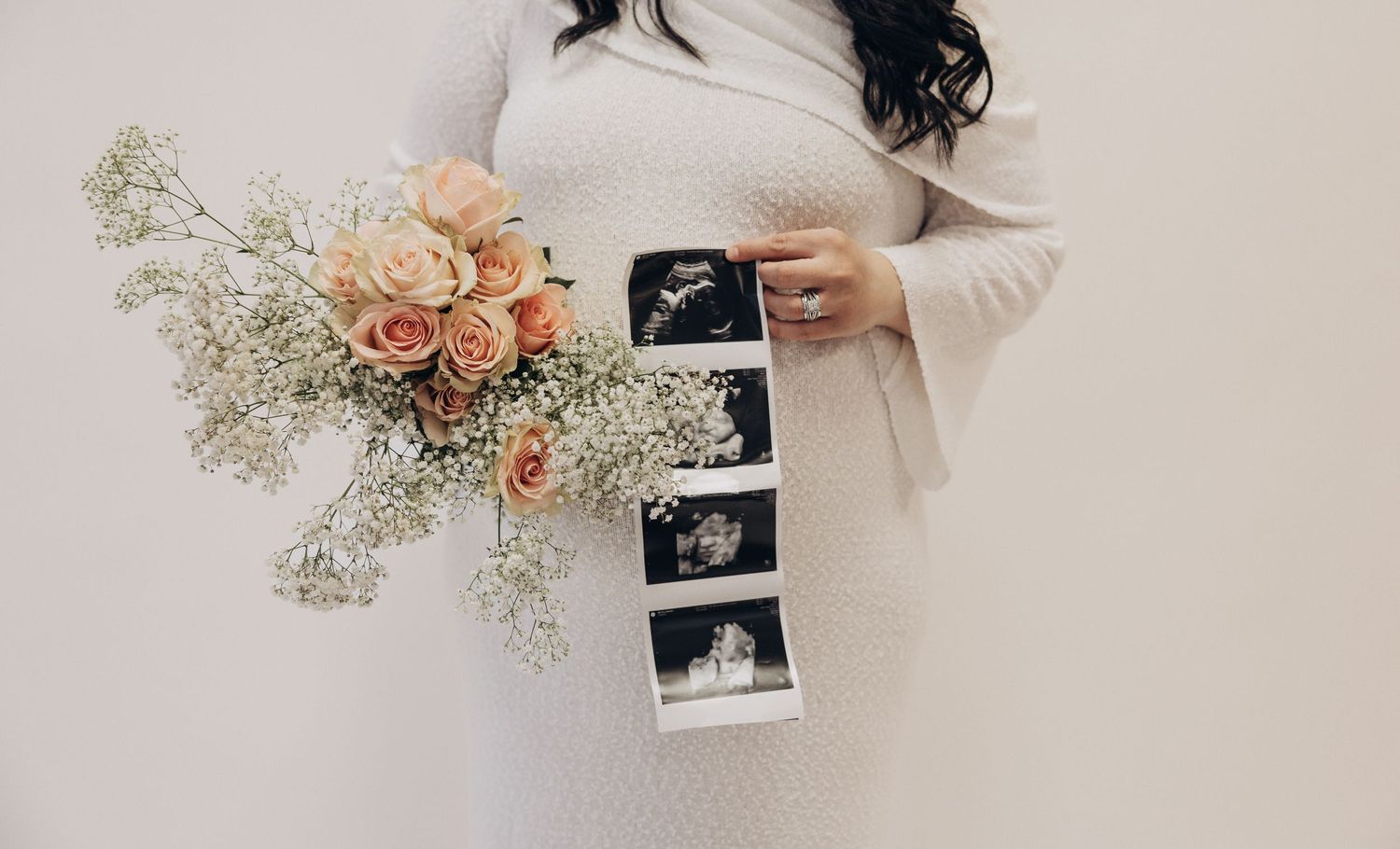 Romantic pregnancy announcement with ultrasound photos and delicate peach roses with baby's breath flowers.