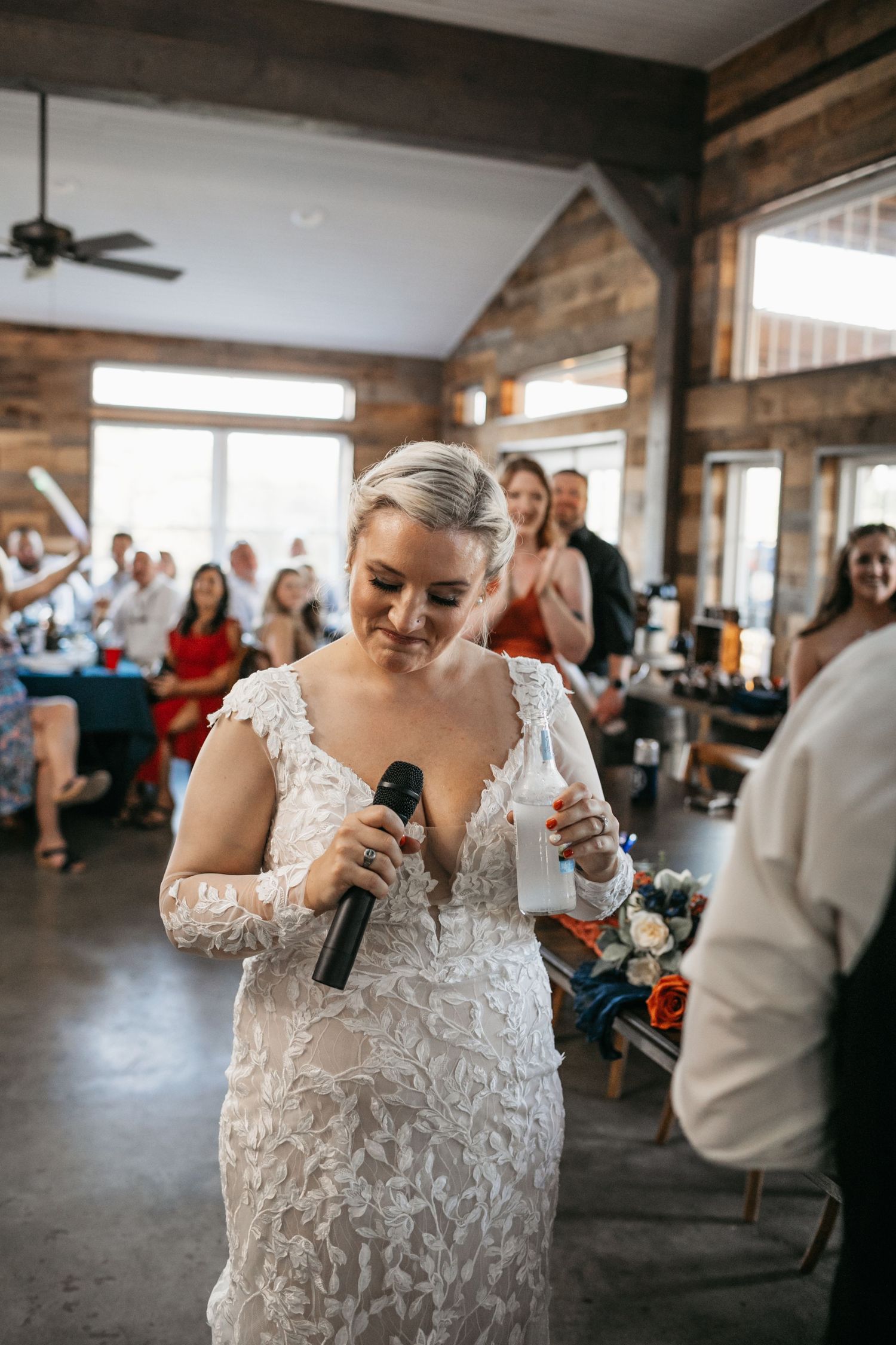 Wedding reception celebration in a rustic indoor venue with exposed wooden beams.
