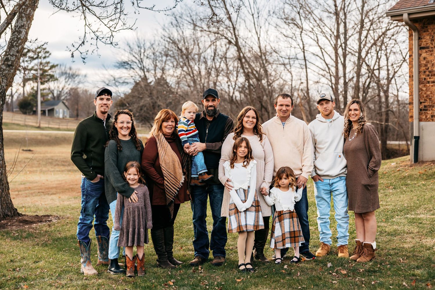 Extended family gathering outdoors with multiple generations posed together in casual attire.