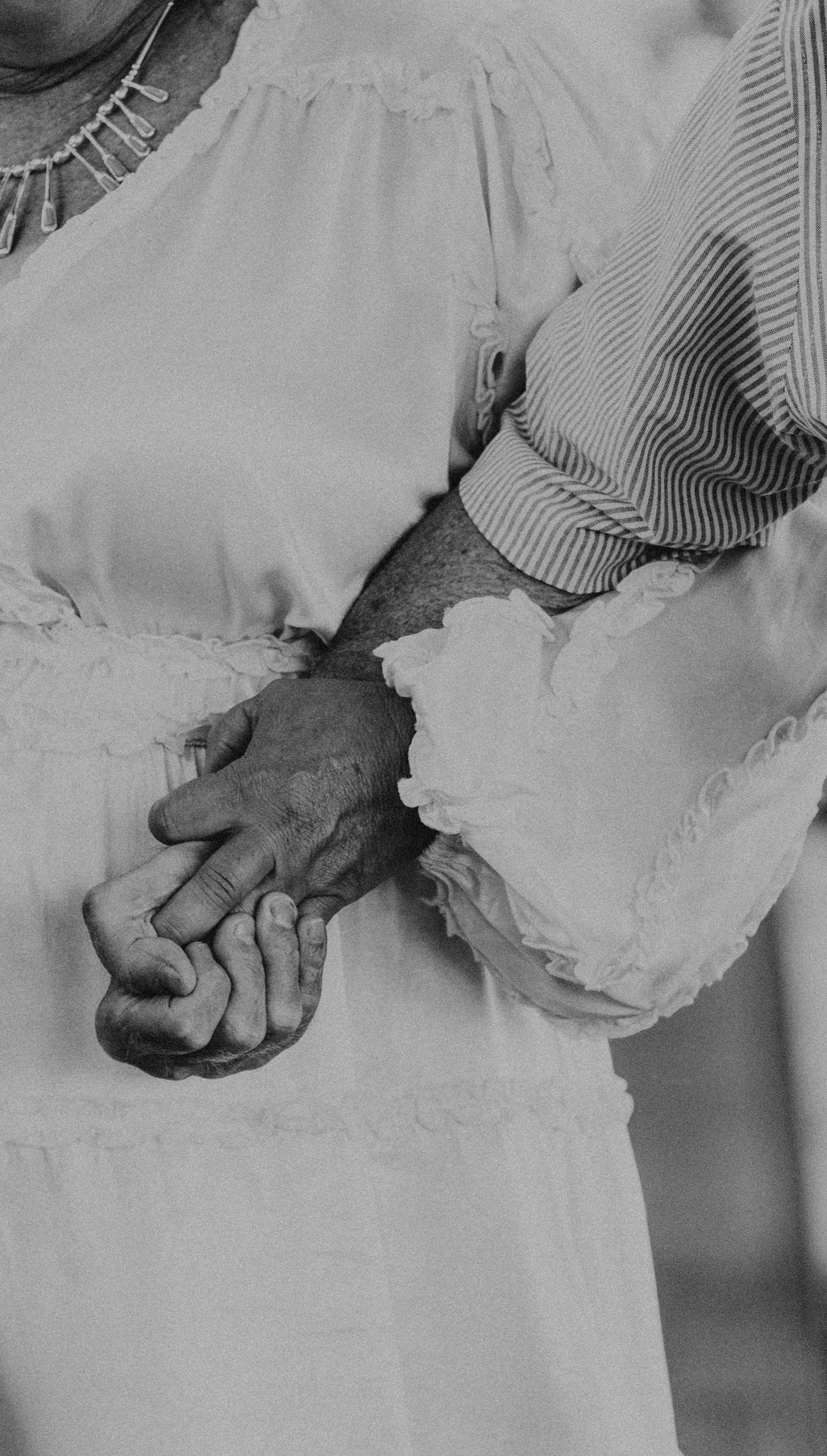 Black and white close-up of hands clasped together in an intimate moment.