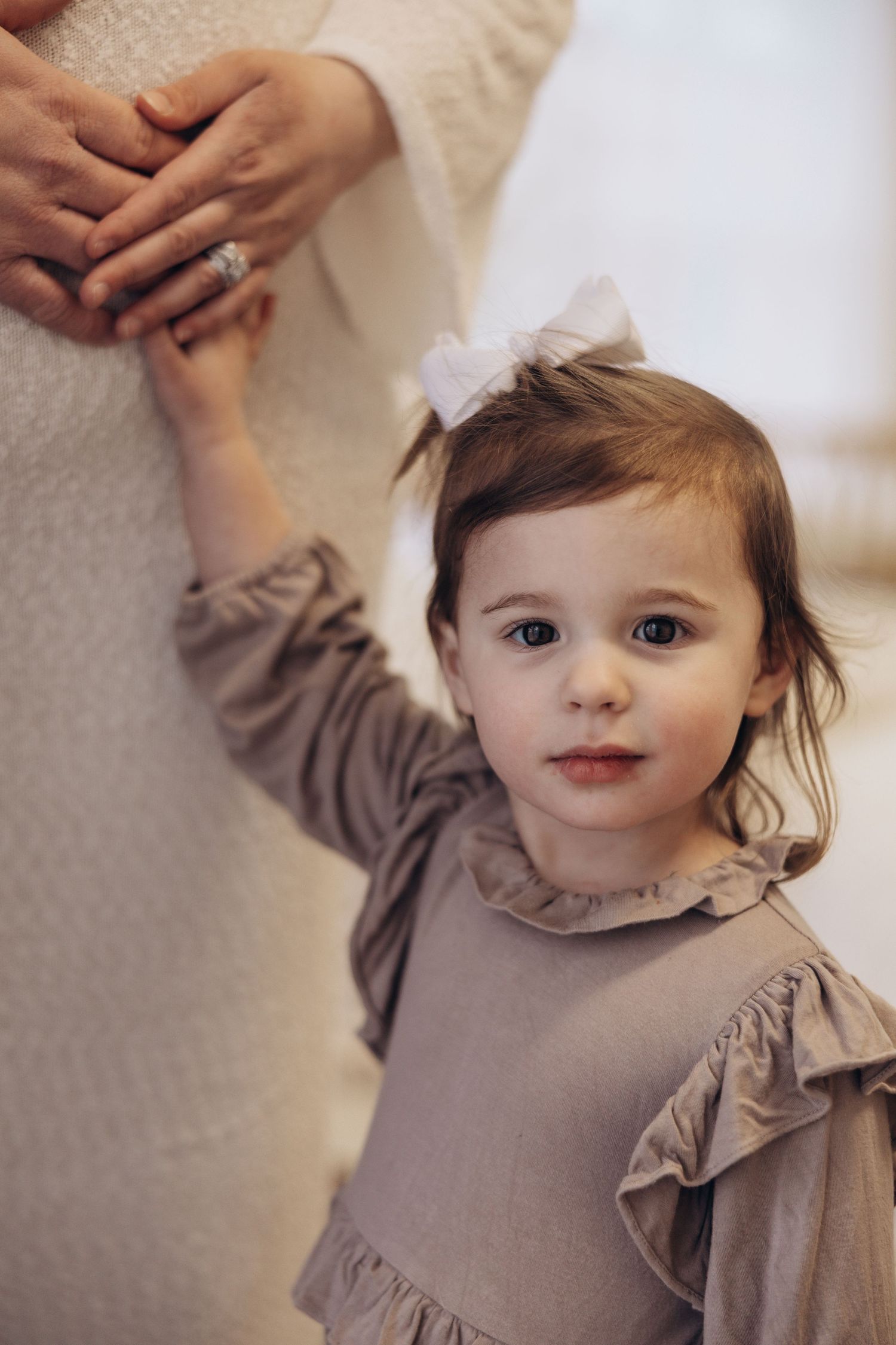 Small child in gray ruffled dress reaches up playfully in series of candid shots.