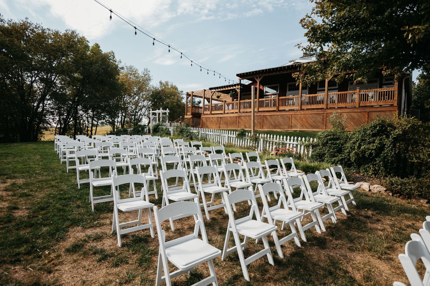 White folding chairs arranged in rows for an outdoor wedding ceremony.