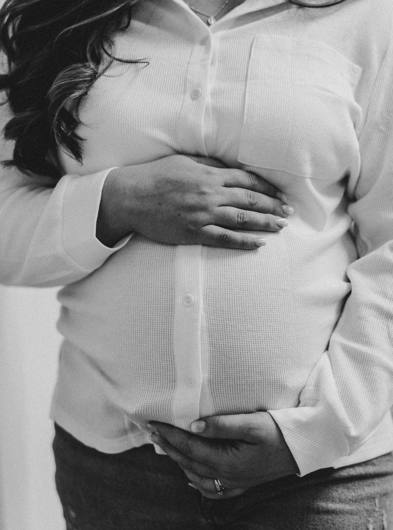 Close-up maternity photo showing hands tenderly placed on stomach .