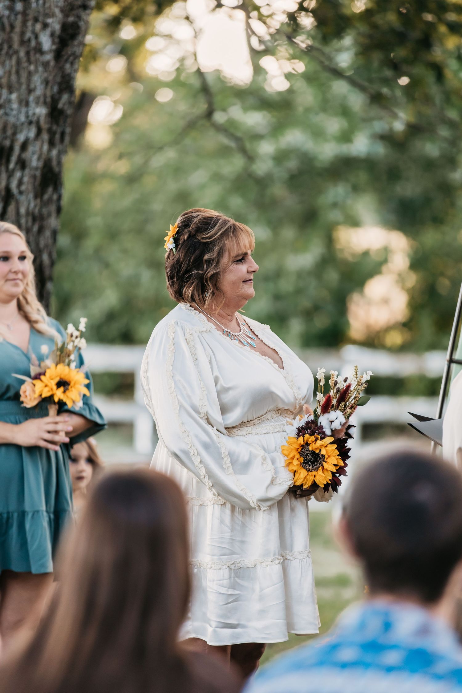 Wedding ceremony in a garden setting with sunflower bouquets and white decorations.