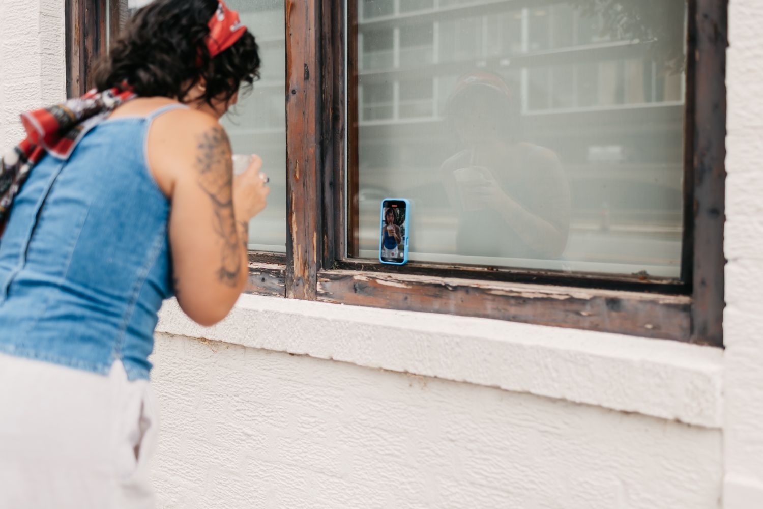 Close-up shot of someone looking through a window wearing denim and a red accessory.