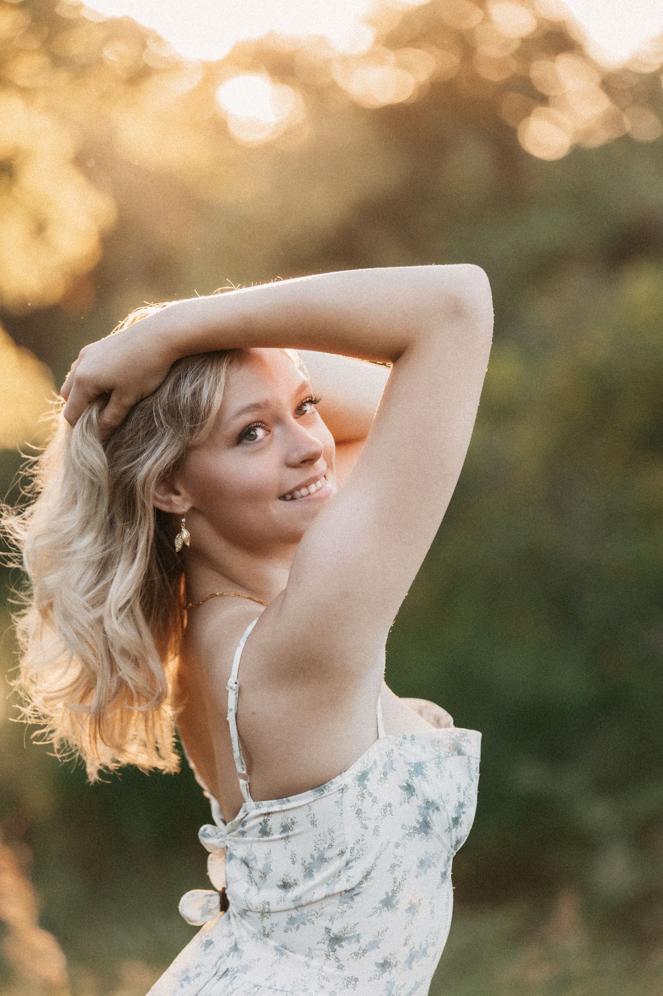 Person in a floral dress twirling gracefully in golden sunlight.