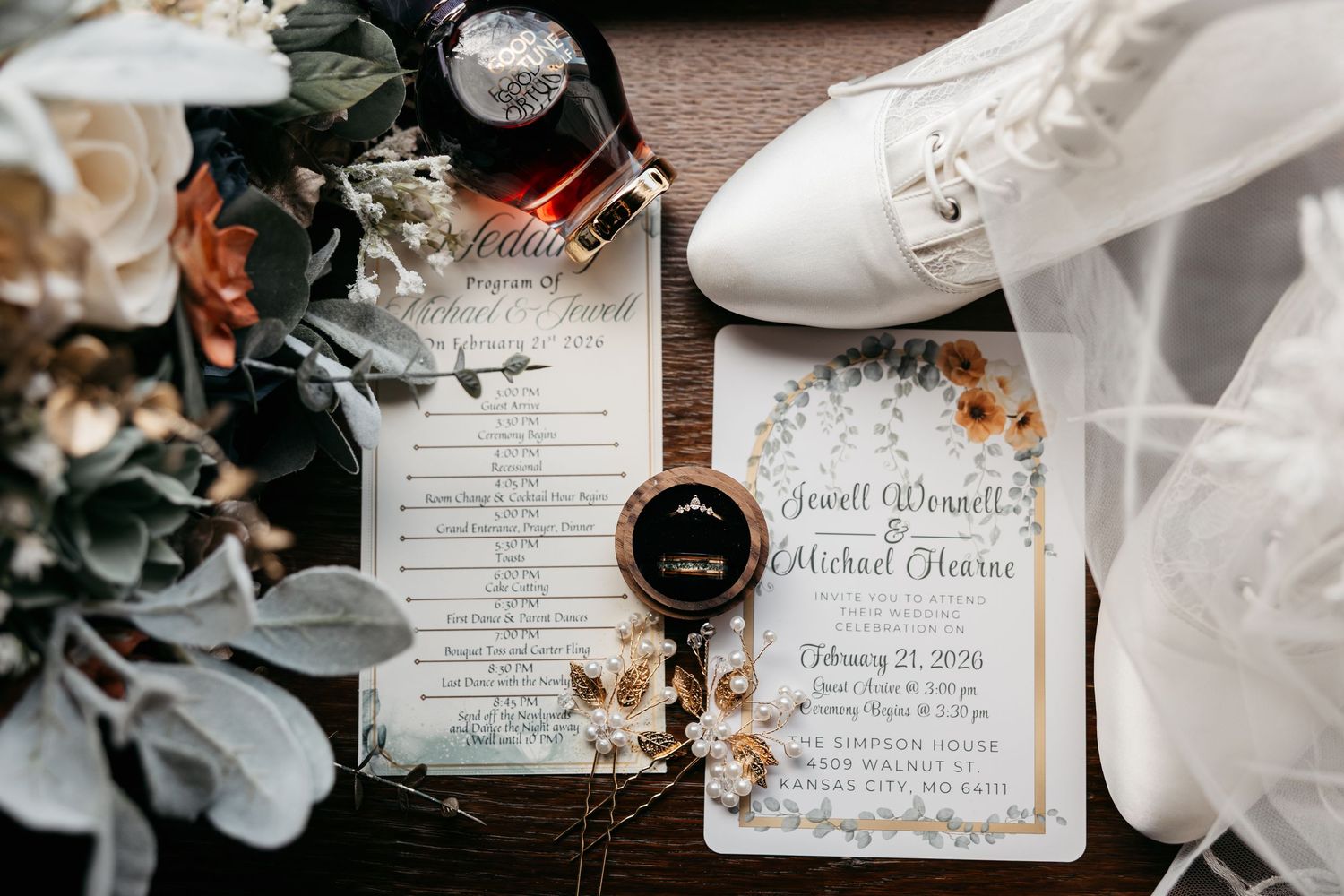 Elegant wedding invitation suite with white flowers and delicate calligraphy displayed on rustic wooden surface.