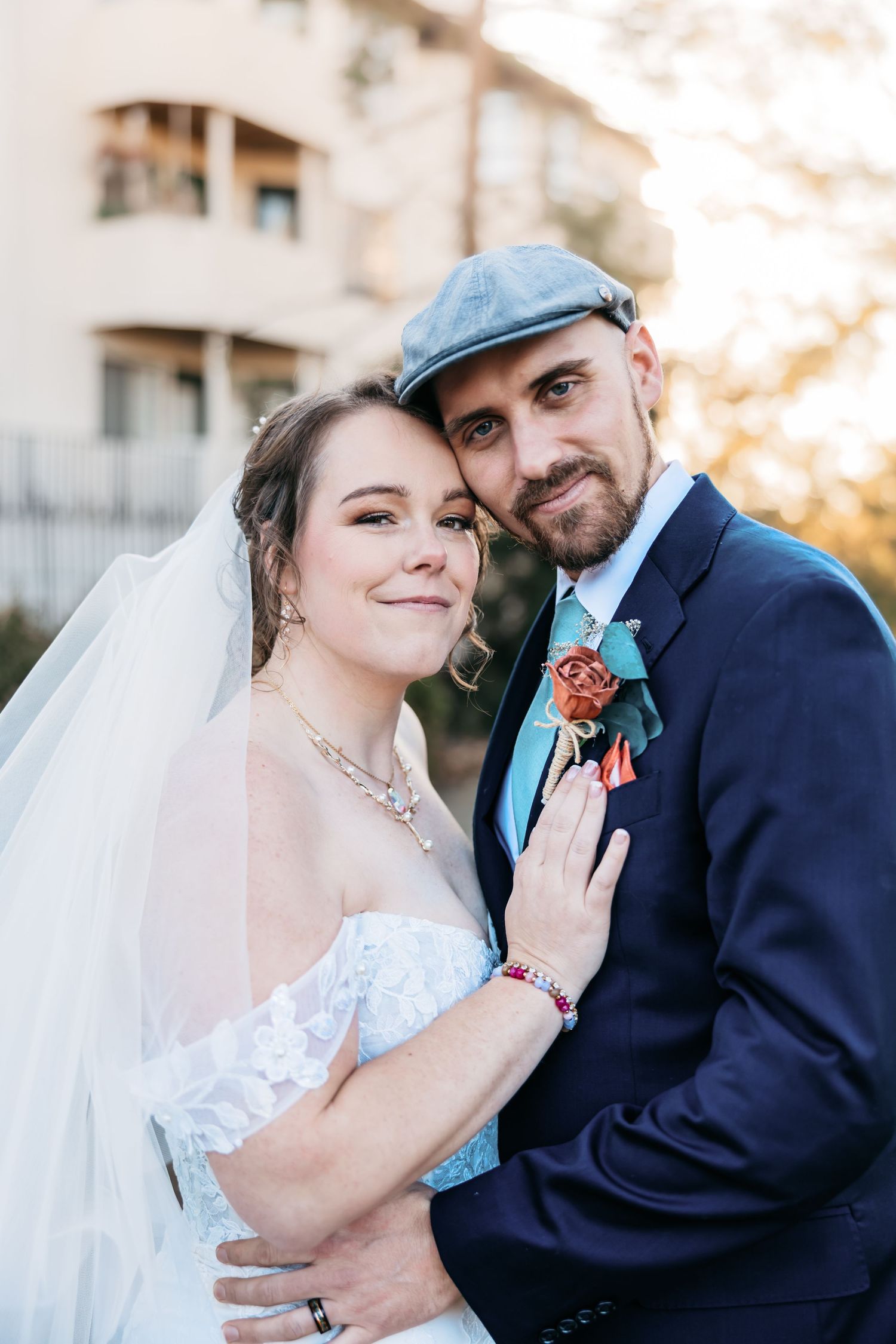Romantic wedding couple embraces outdoors in formal attire with bride in white dress and groom in navy suit.