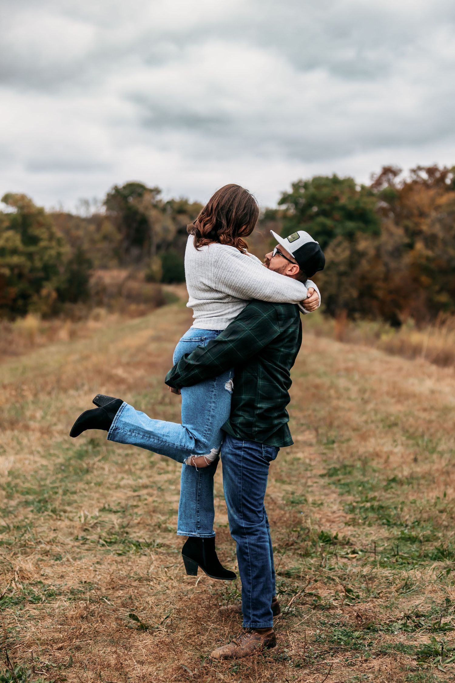 Playful couple spinning and embracing in an autumn field.