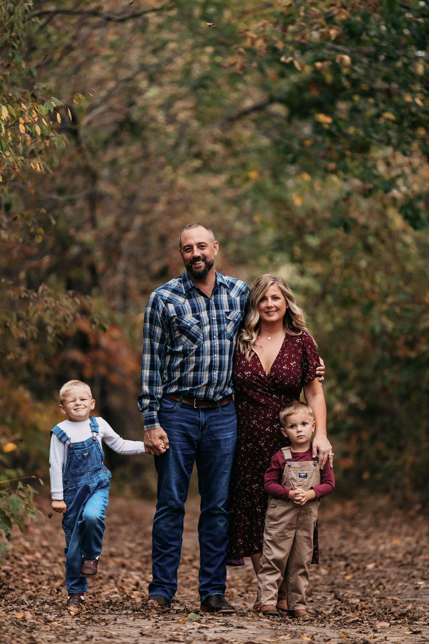 Family walking together through fallen leaves on an autumn trail.