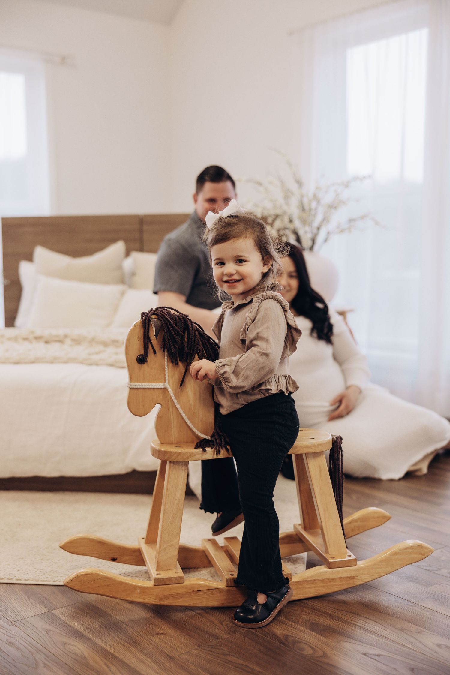 Child plays on wooden rocking horse in bright, minimalist room setting.