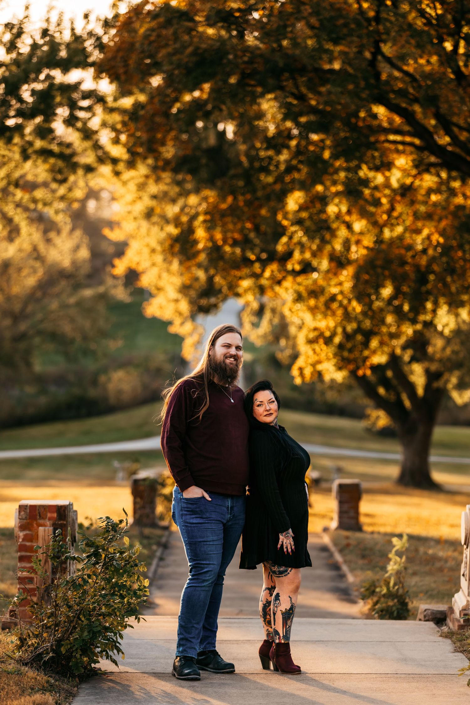 A couple shares romantic moments on a tree-lined path during golden hour.