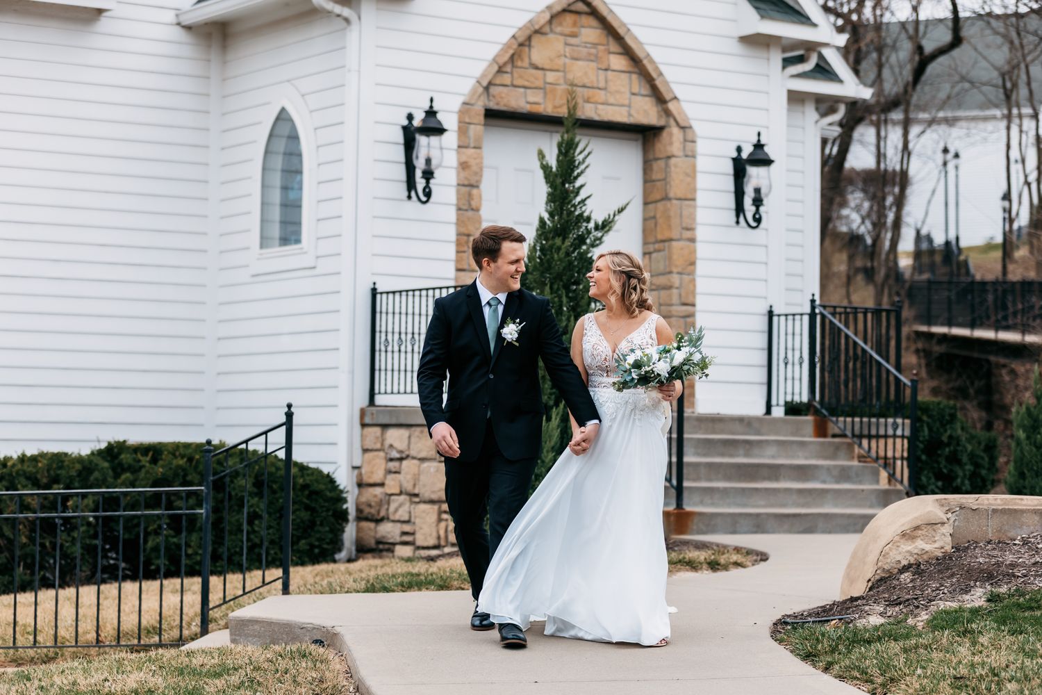 Elegant white chapel provides backdrop for wedding couple portraits.