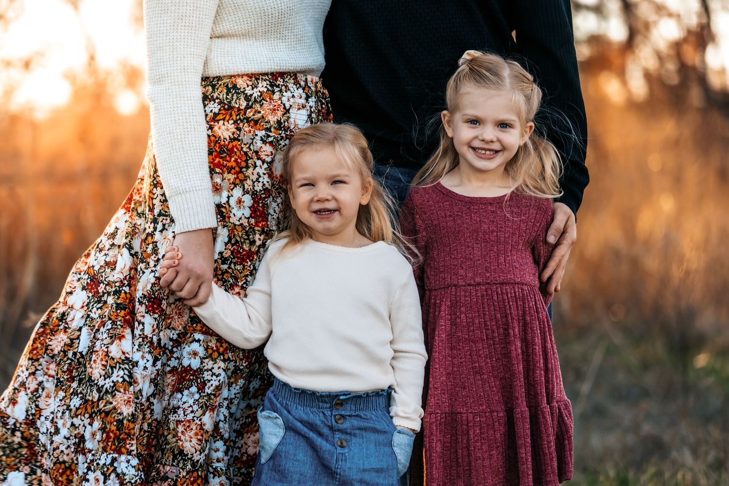 Children in coordinated fall outfits playing outdoors during sunset.