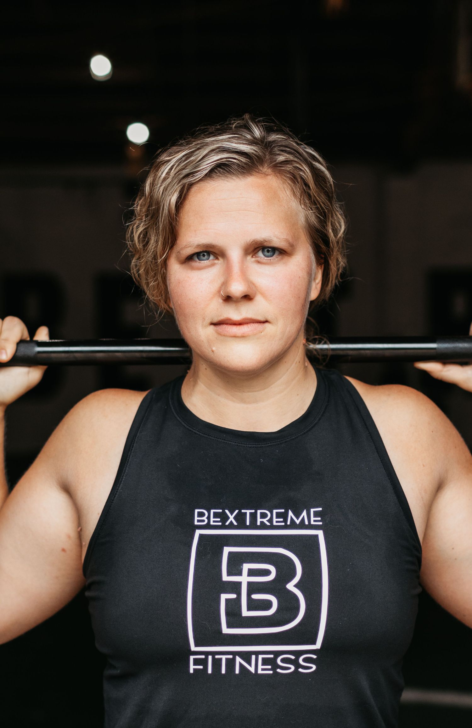 Athlete wearing black tank top with Bextreme Fitness logo during weightlifting session.