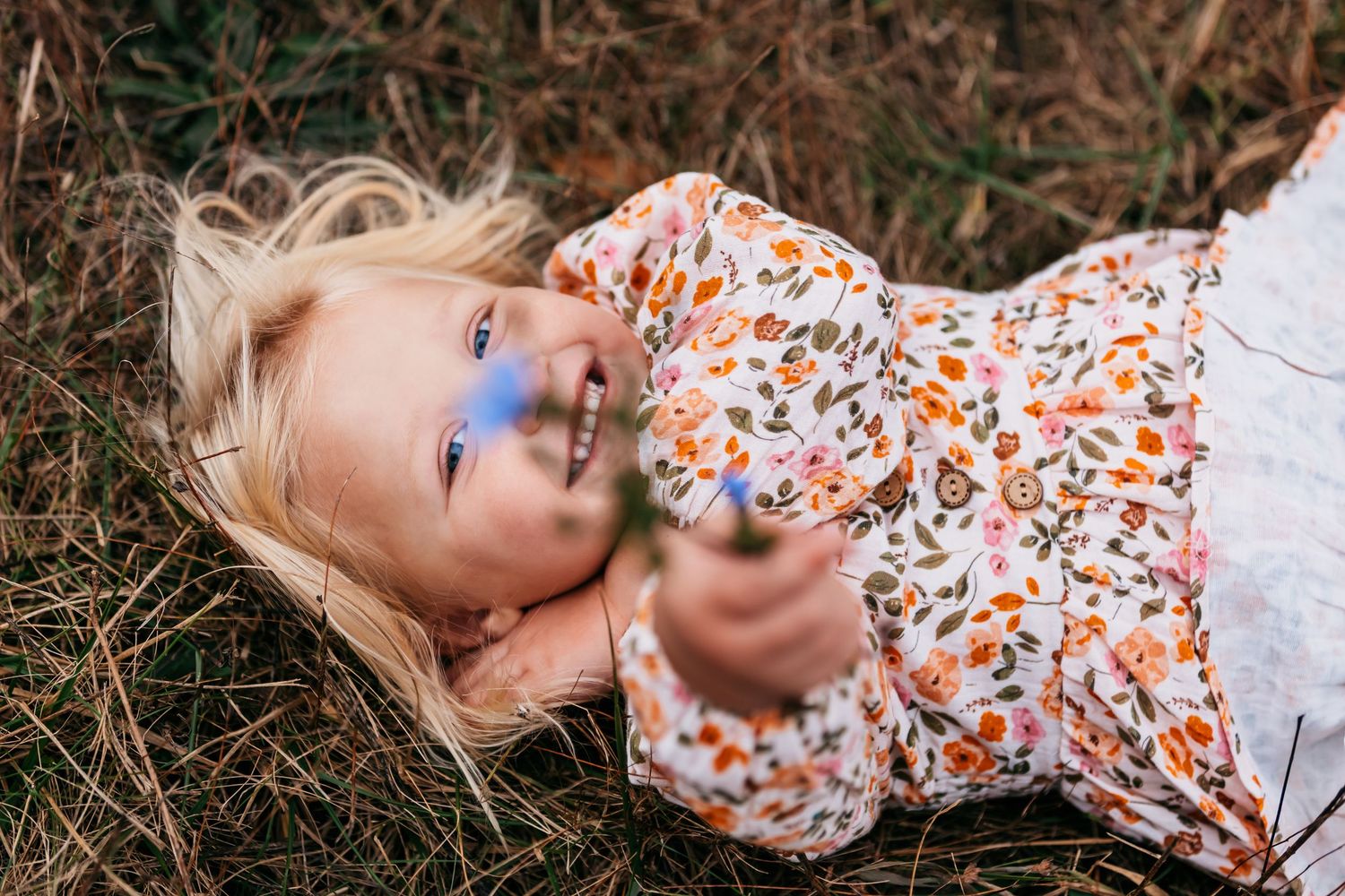 A series of artistic portraits showing someone lying in autumn leaves wearing a floral dress.