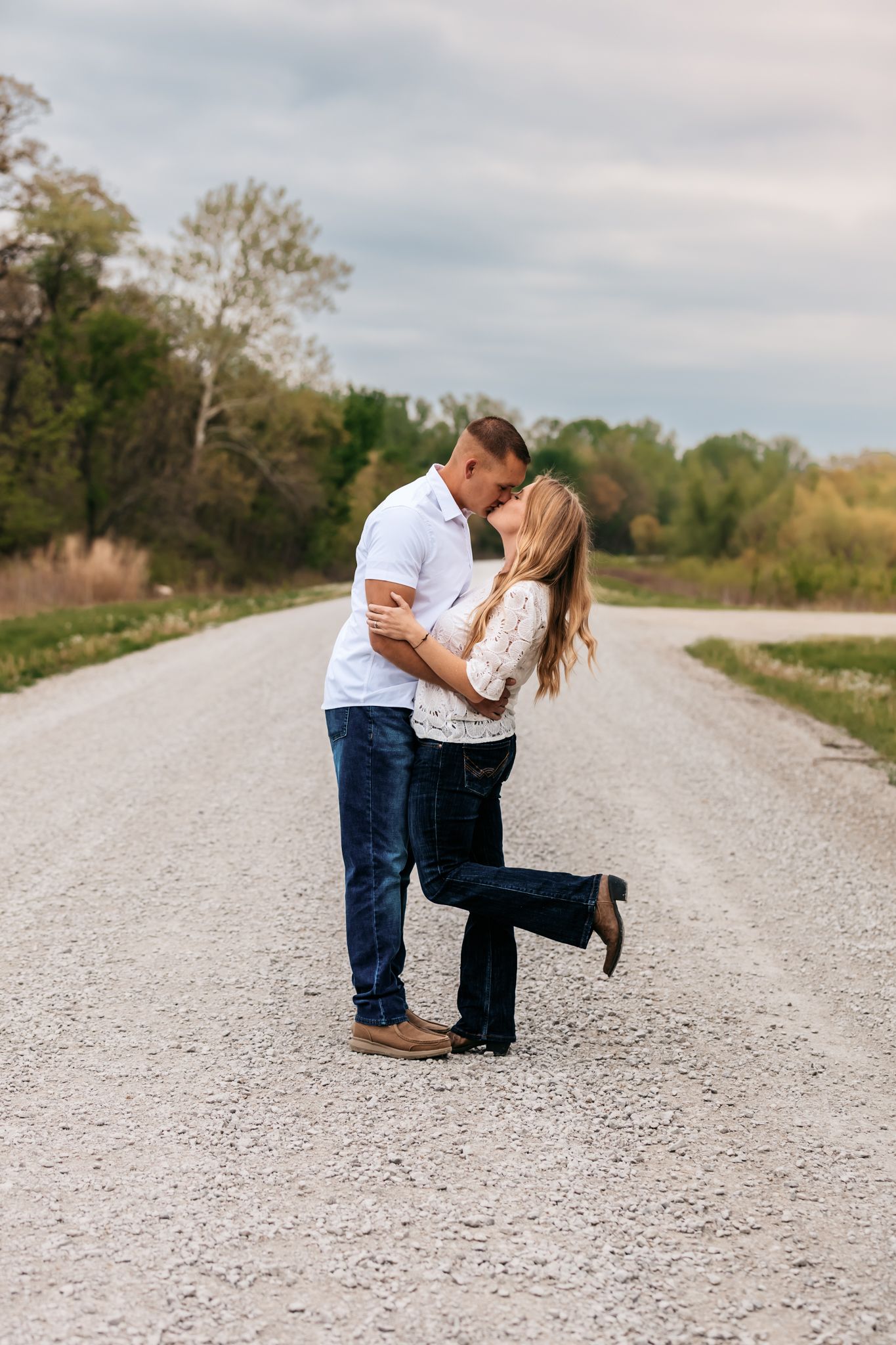 Couple sharing romantic moments on a gravel road during engagement photoshoot.