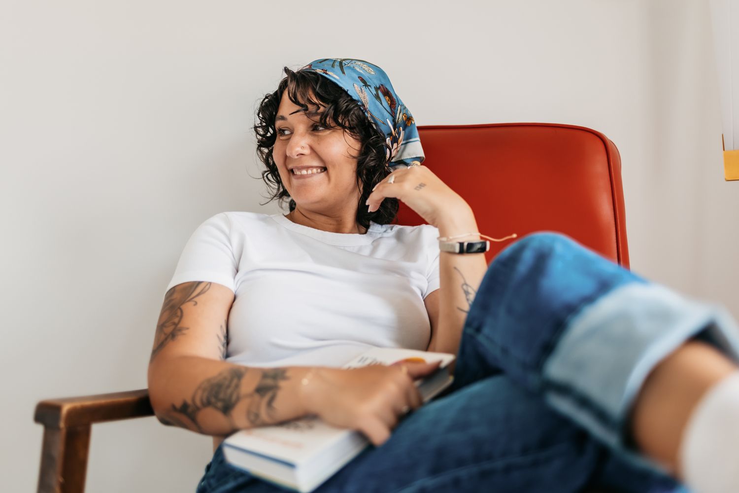 Casual lifestyle portrait in a red chair wearing a blue bandana and white t-shirt.