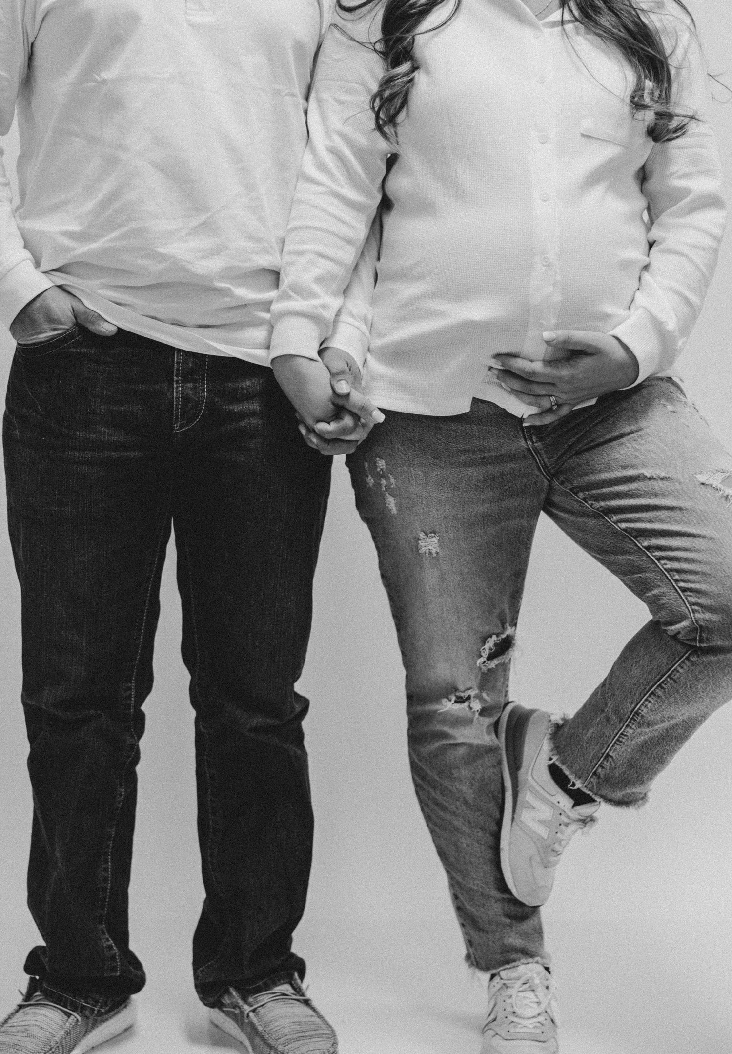 Lower body shots of two people in jeans standing together against neutral background.