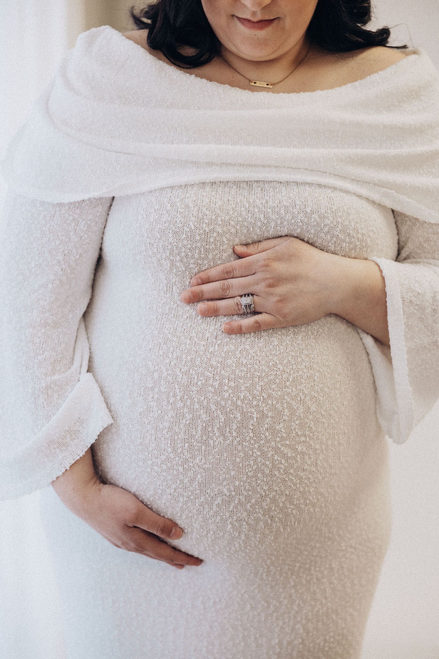 Close-up shots of pregnant belly in white textured sweater.