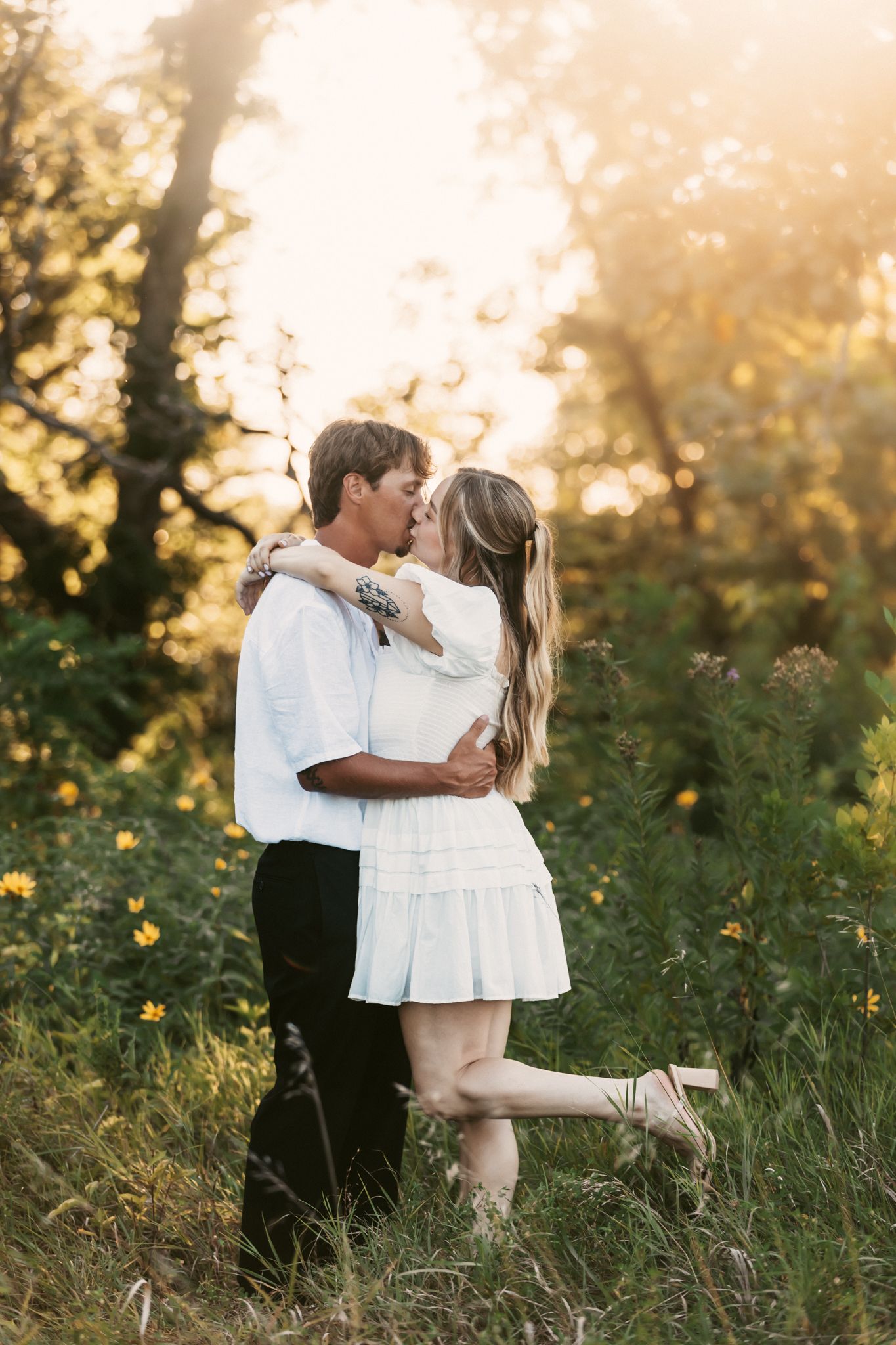 Romantic embrace in a wildflower meadow during golden hour sunset.