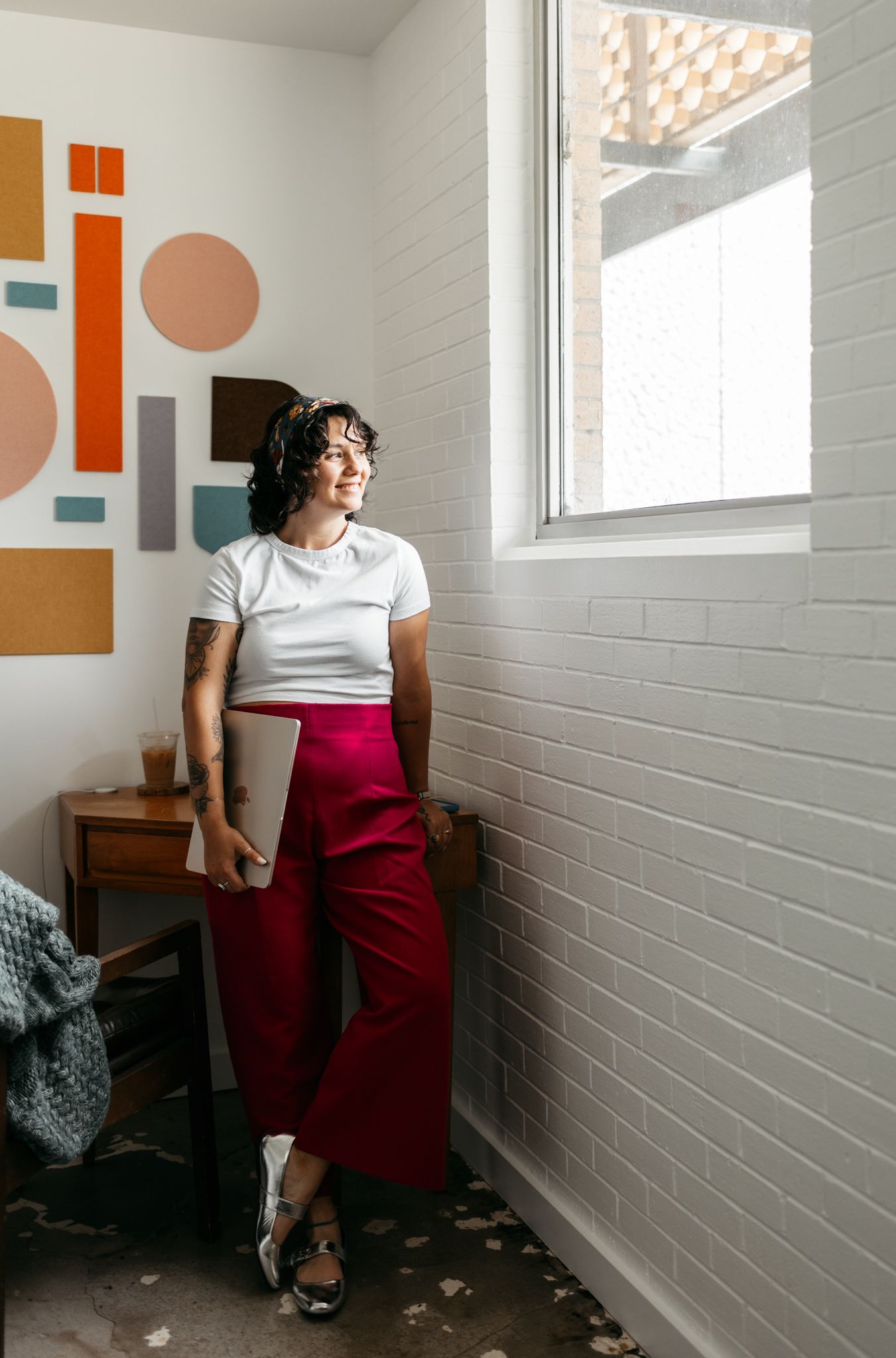 Modern interior with geometric wall art, white brick walls, and red wide-leg pants styling.