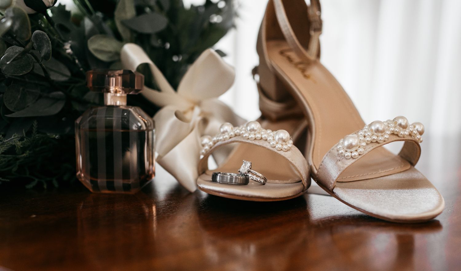 Elegant bridal accessories including rose gold shoes and jewelry on white surface.