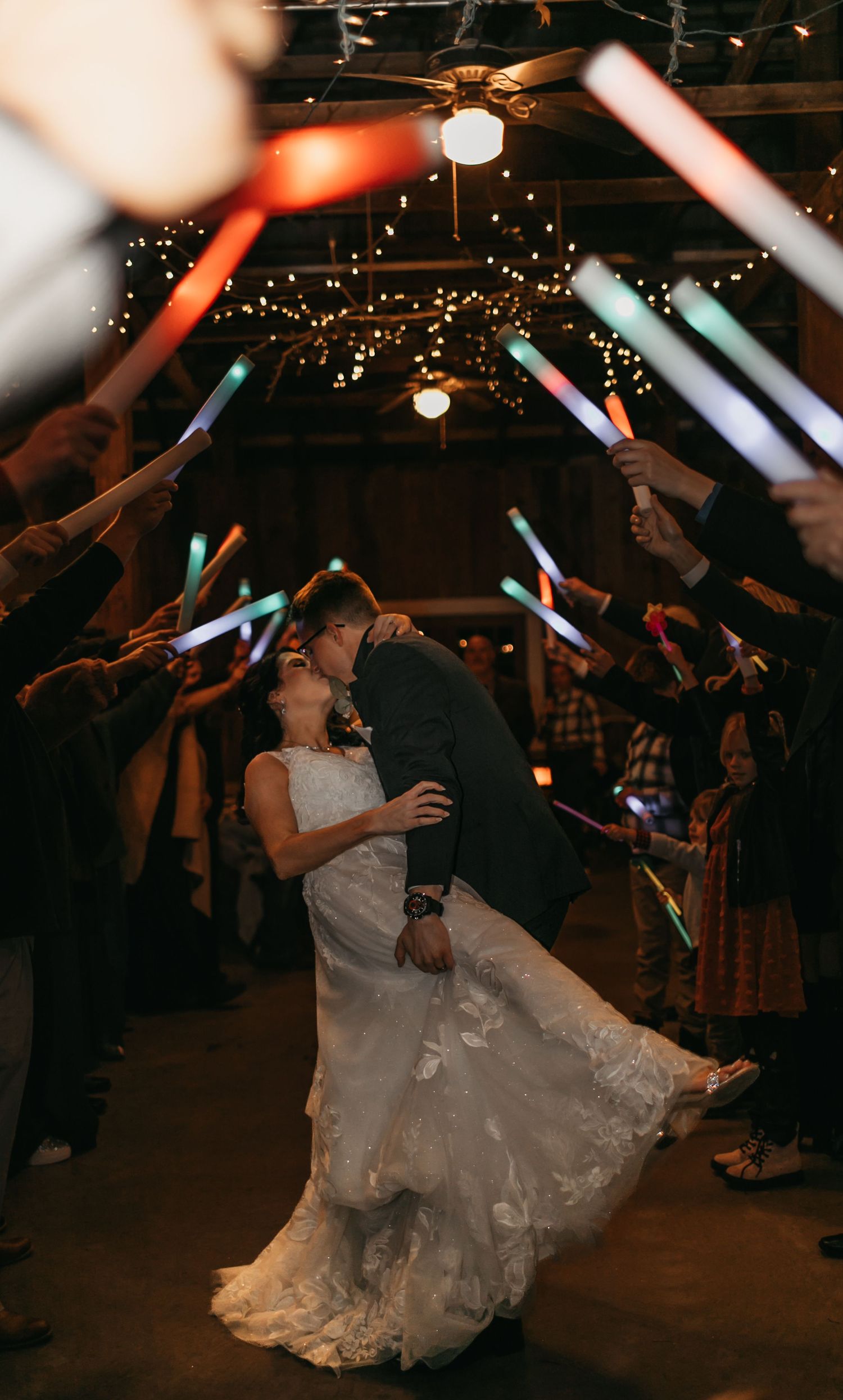 Wedding guests hold glowing LED foam sticks during a nighttime reception celebration.