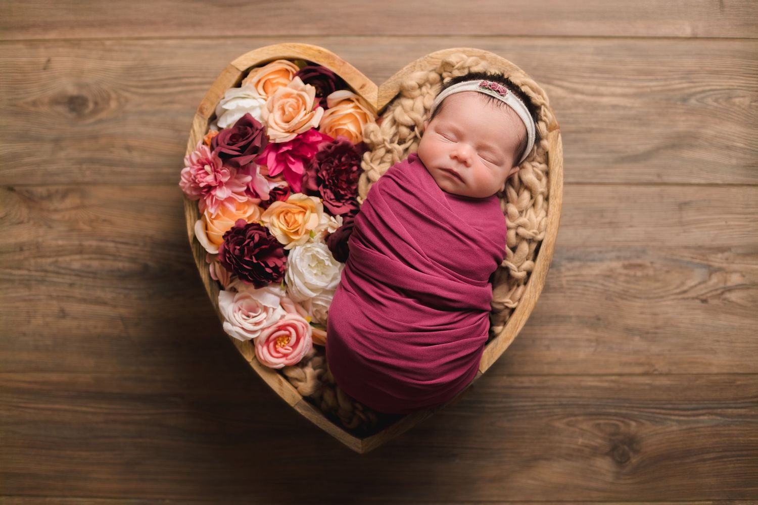 Wooden backdrop with floral decorations and props arranged for newborn photography.