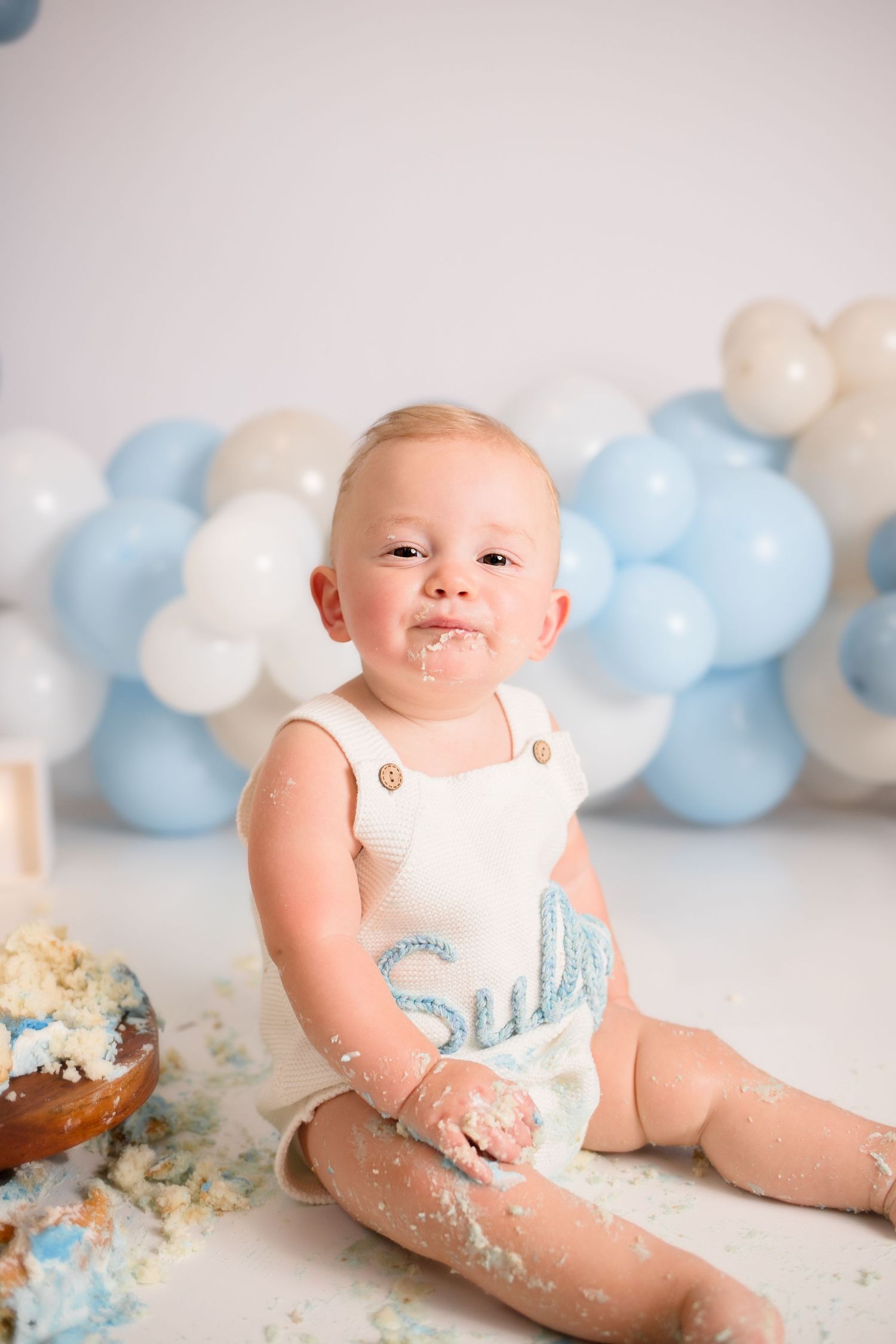 First birthday cake smash session with blue balloon decorations.