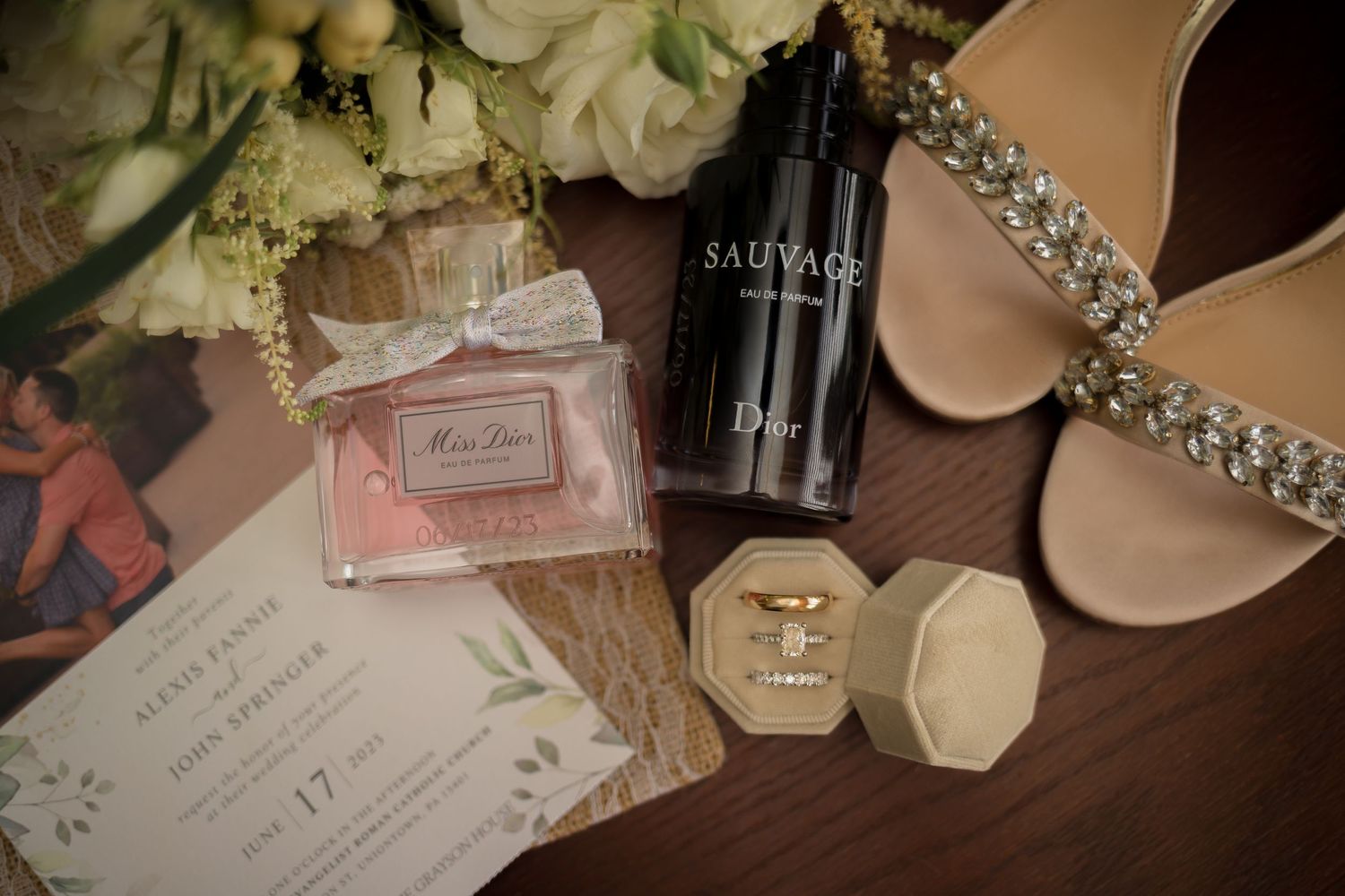 Wedding detail shot showing perfume bottles, jewelry, and invitation details arranged artistically.