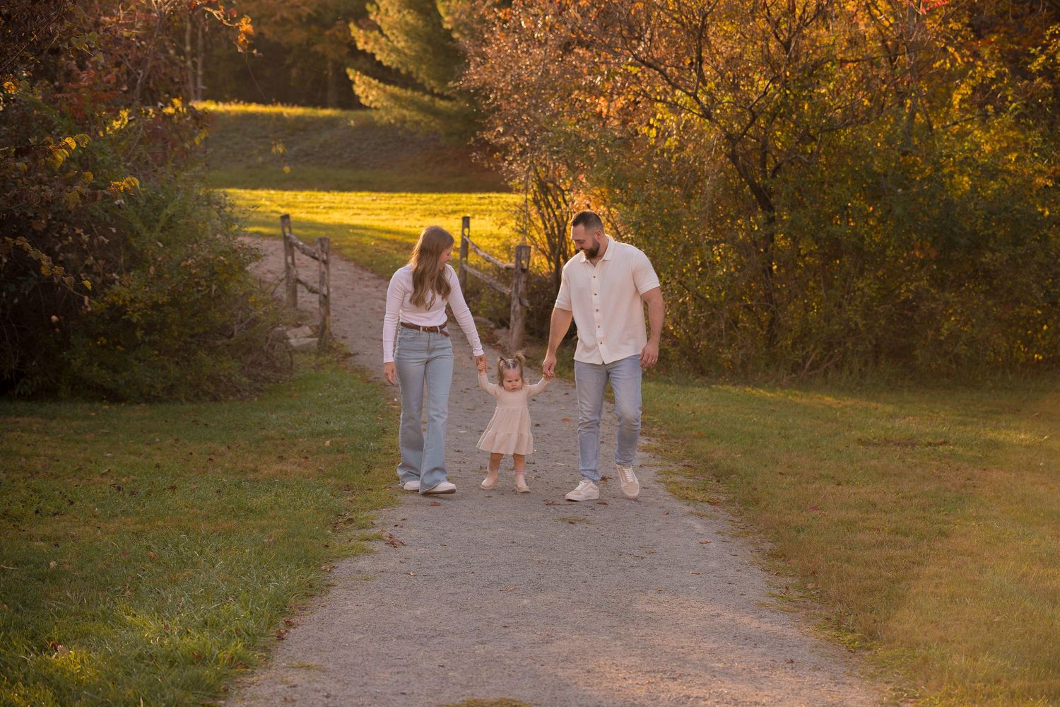 People walking along a path surrounded by fall foliage at sunset.