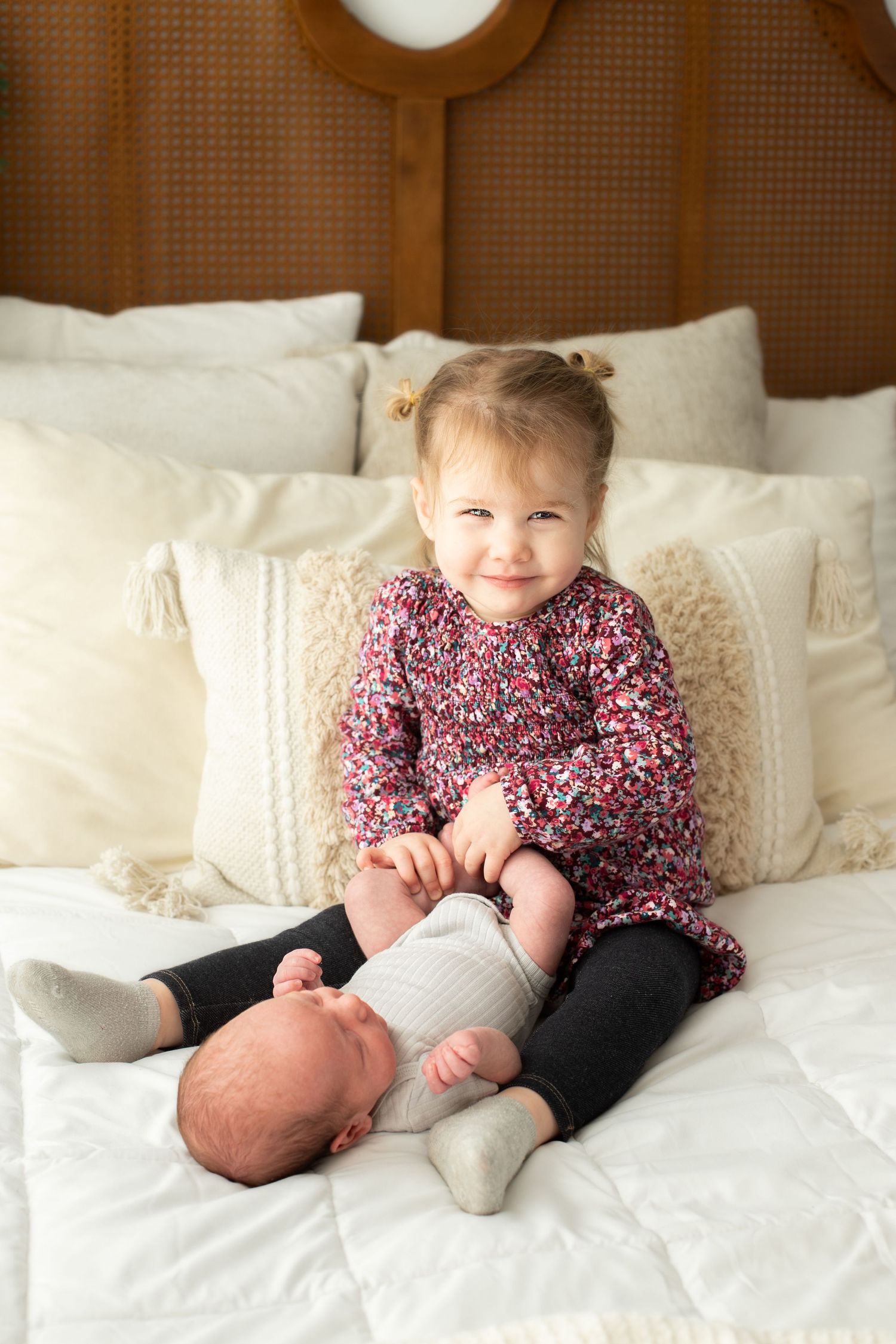 Children in floral print clothing relaxing on white bedding.