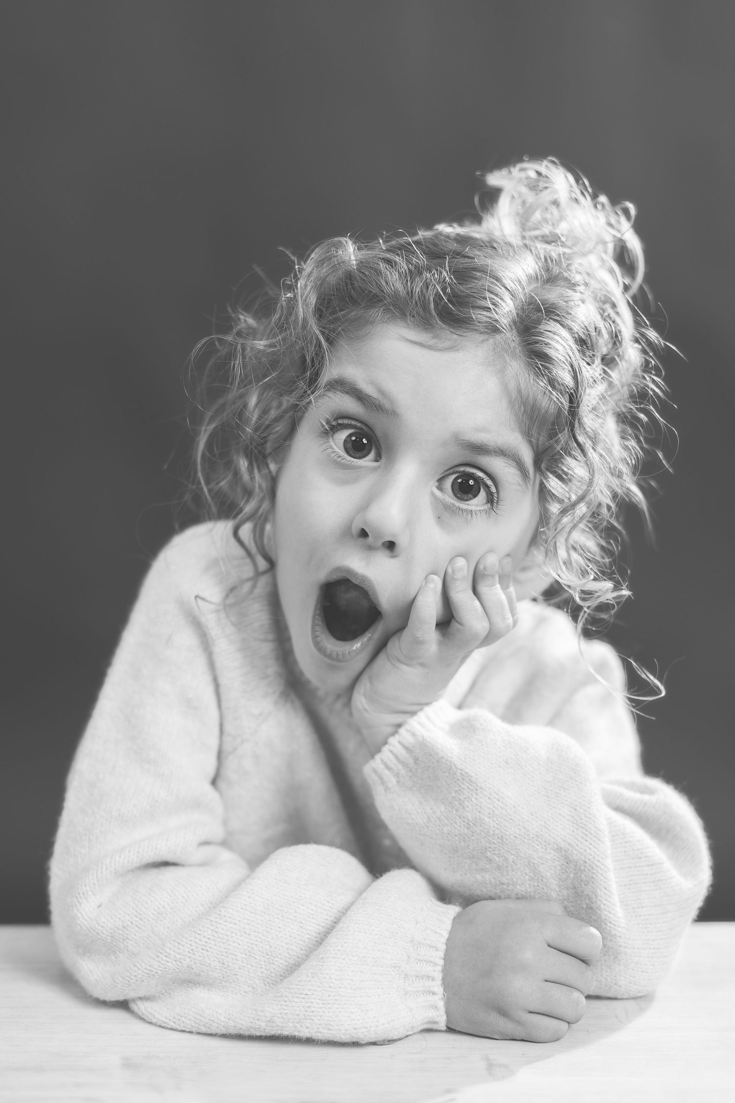 A series of black and white portraits showing playful expressions and poses in a soft, dreamy style.