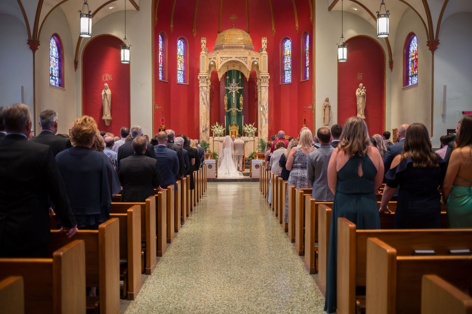 Interior view of a traditional church wedding ceremony with guests seated in wooden pews.