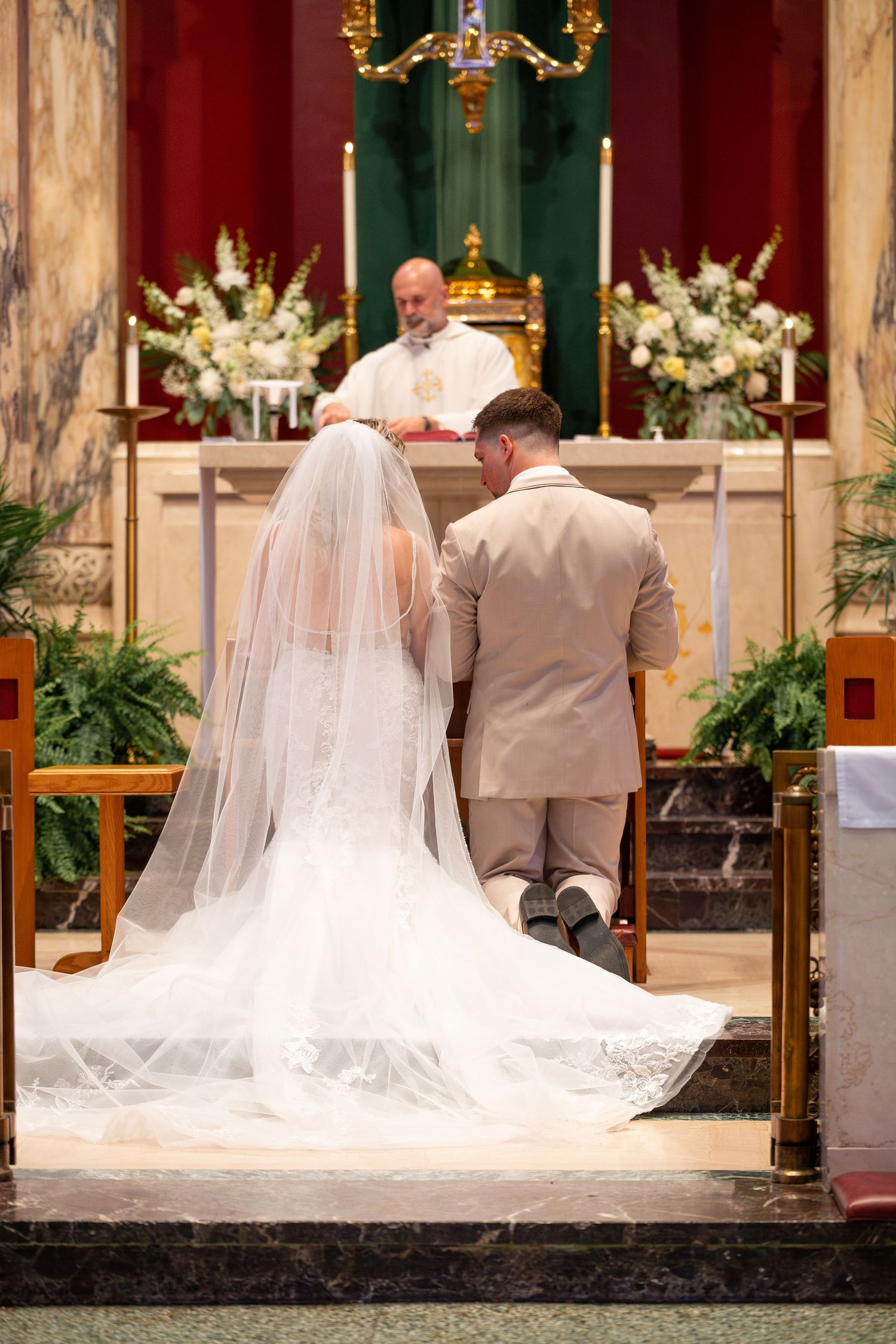 A wedding ceremony at an altar with flowing white veil and traditional church decor.
